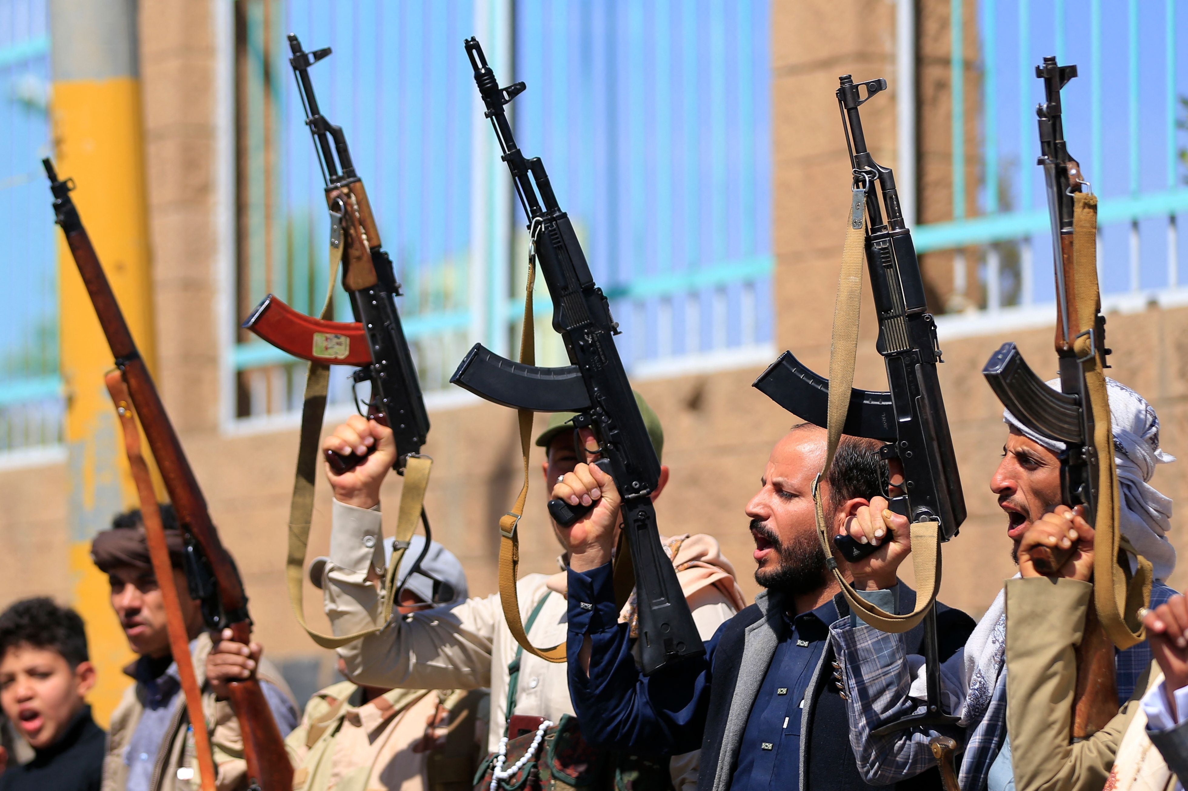 Mehrere bewaffnete Männer heben bei einer Kundgebung in Sanaa gemeinsam ihre Gewehre in die Luft.