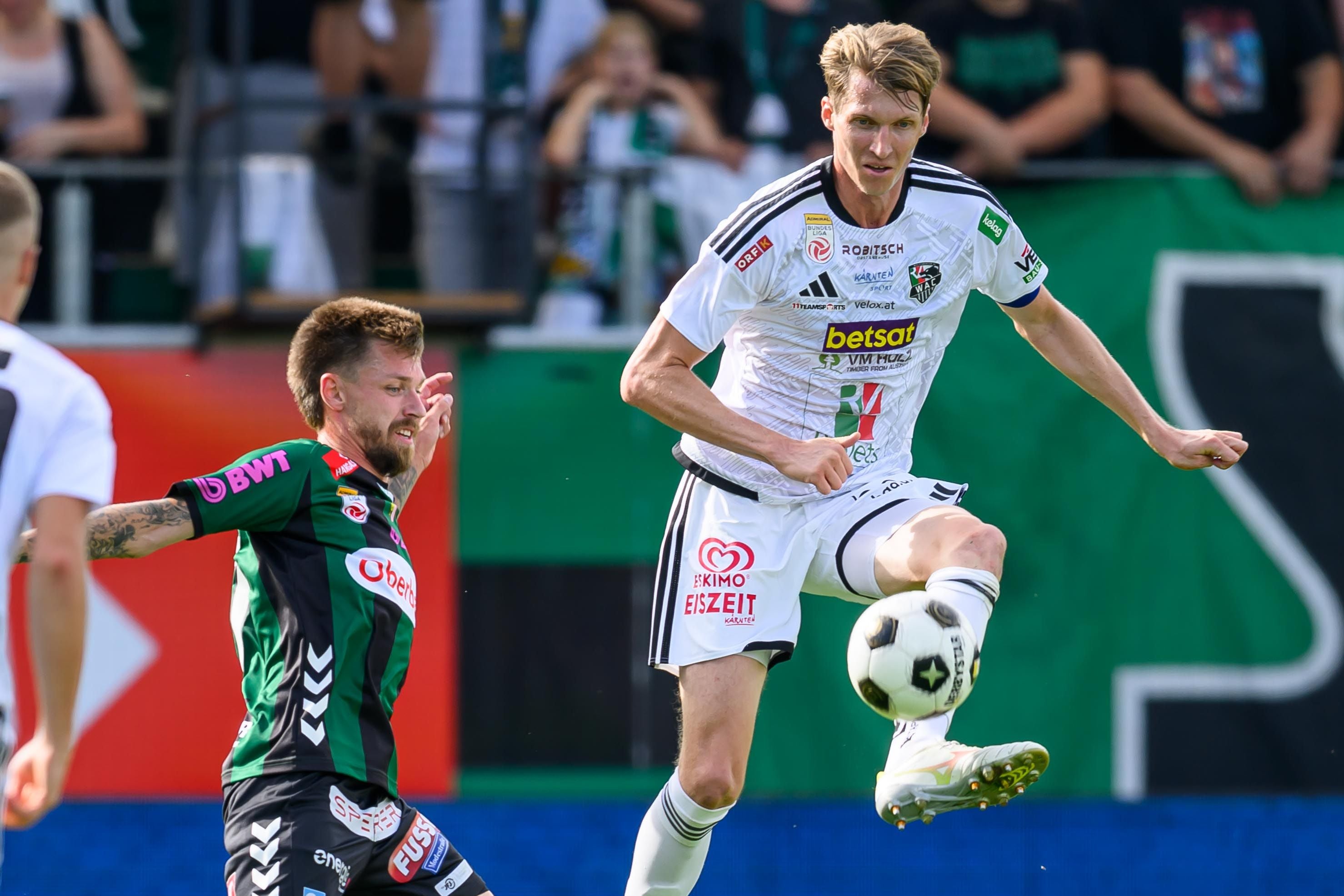 WAC-Kapitän Simon Piesinger dribbelt im weiß-schwarzen Trikot fokussiert den Ball während eines Bundesligaspiels.