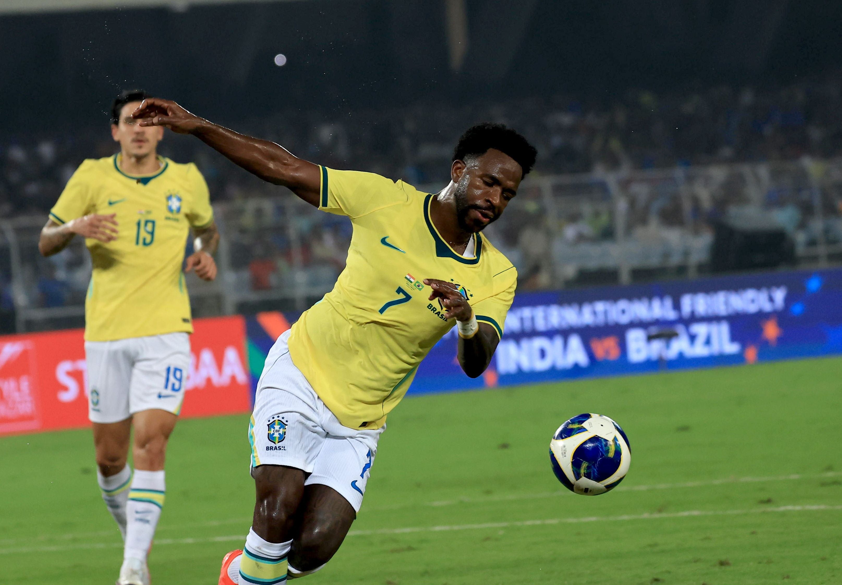 Brasilianischer Fußballspieler im gelben Trikot beim Spiel gegen Indien, Ball am Boden.