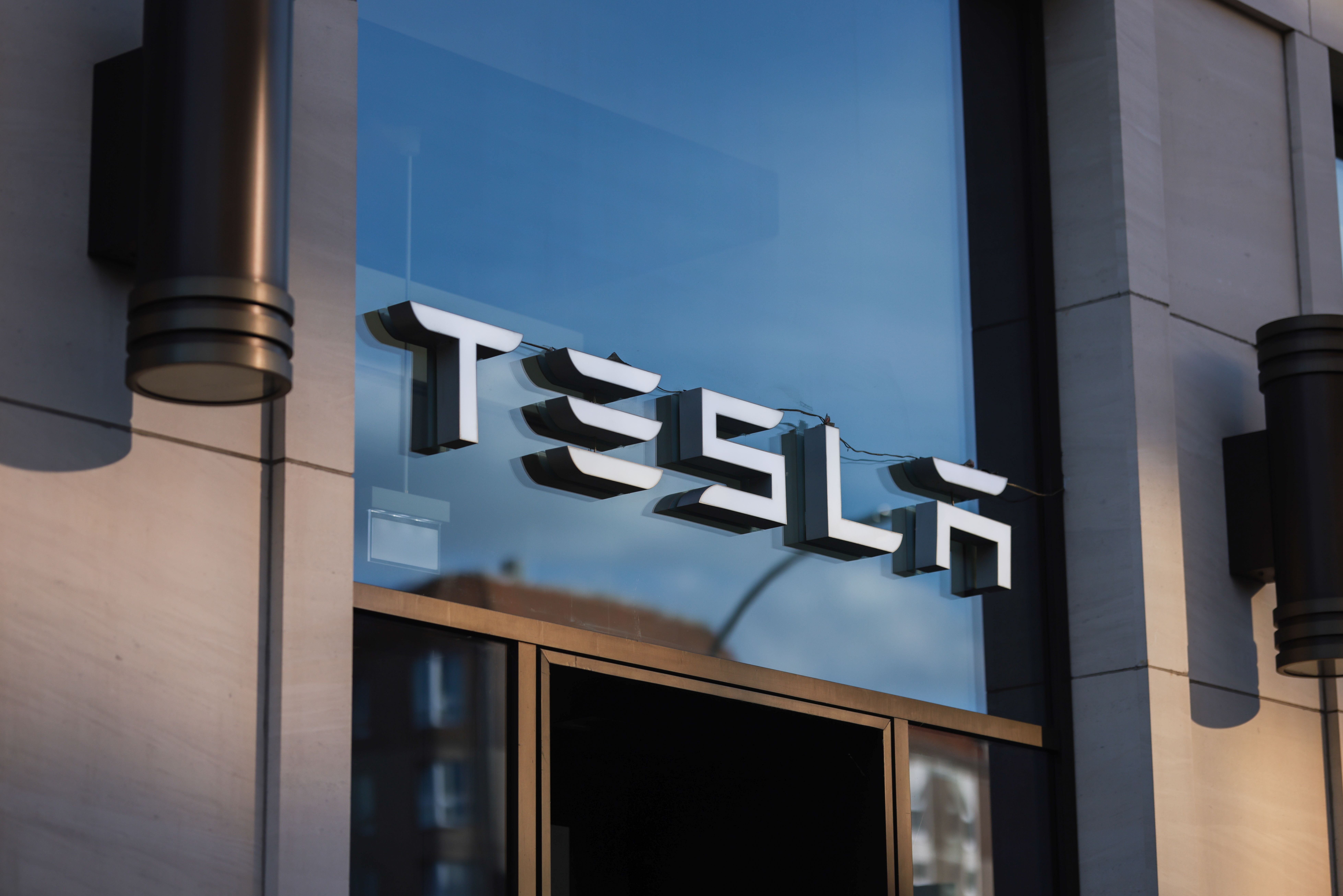 Außenansicht eines Tesla-Geschäfts mit großem Tesla-Logo an der Glasfassade.