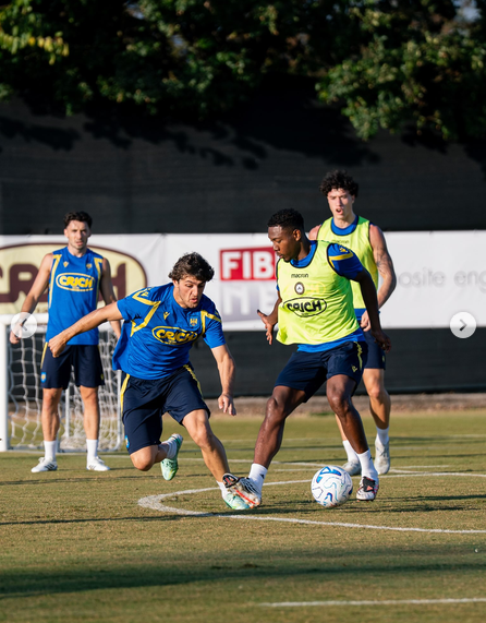 Vier Fußballspieler beim Training, zwei kämpfen um den Ball auf dem Spielfeld.