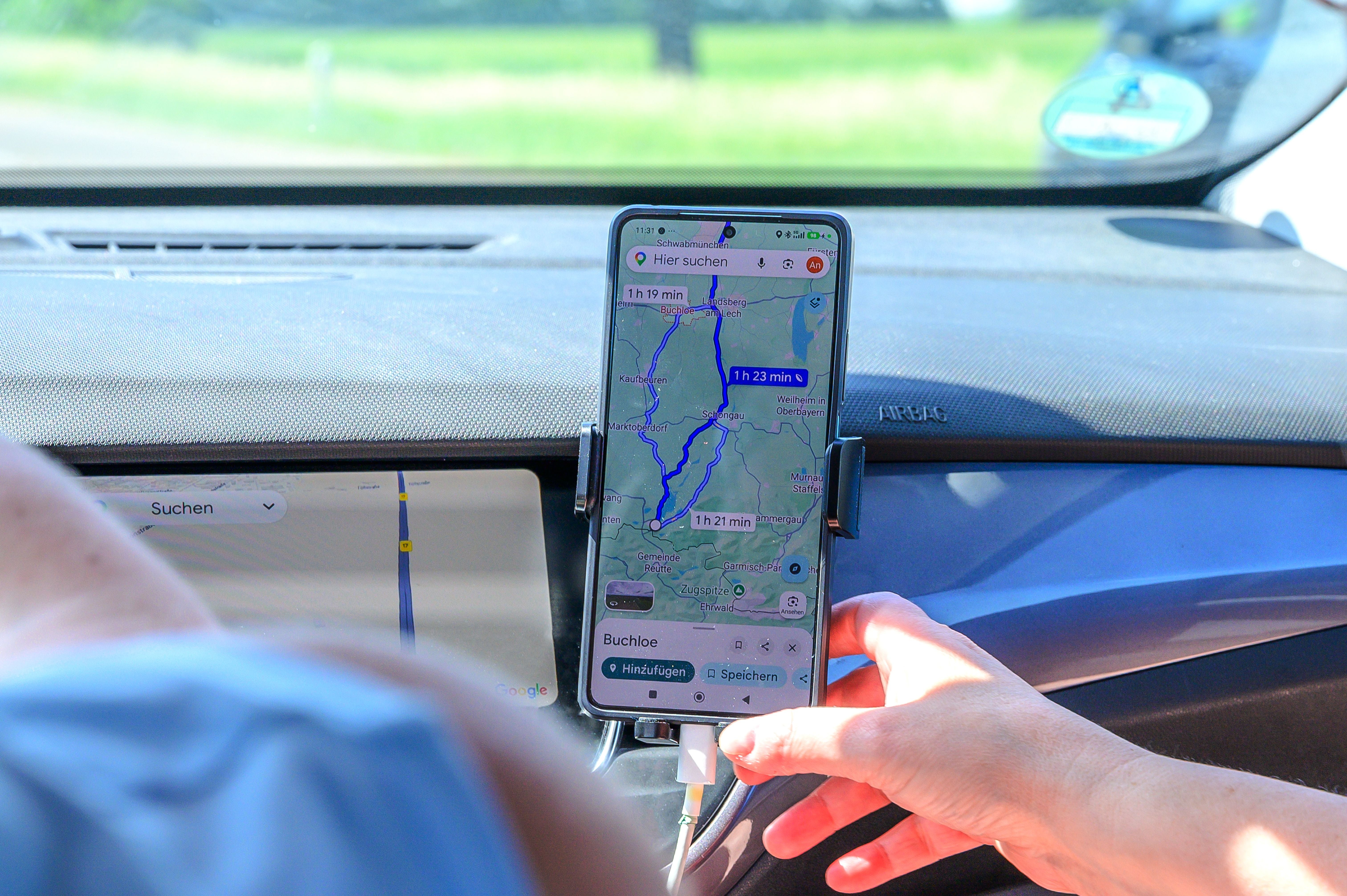 Eine Person stellt im Auto eine Google Maps Route ein.