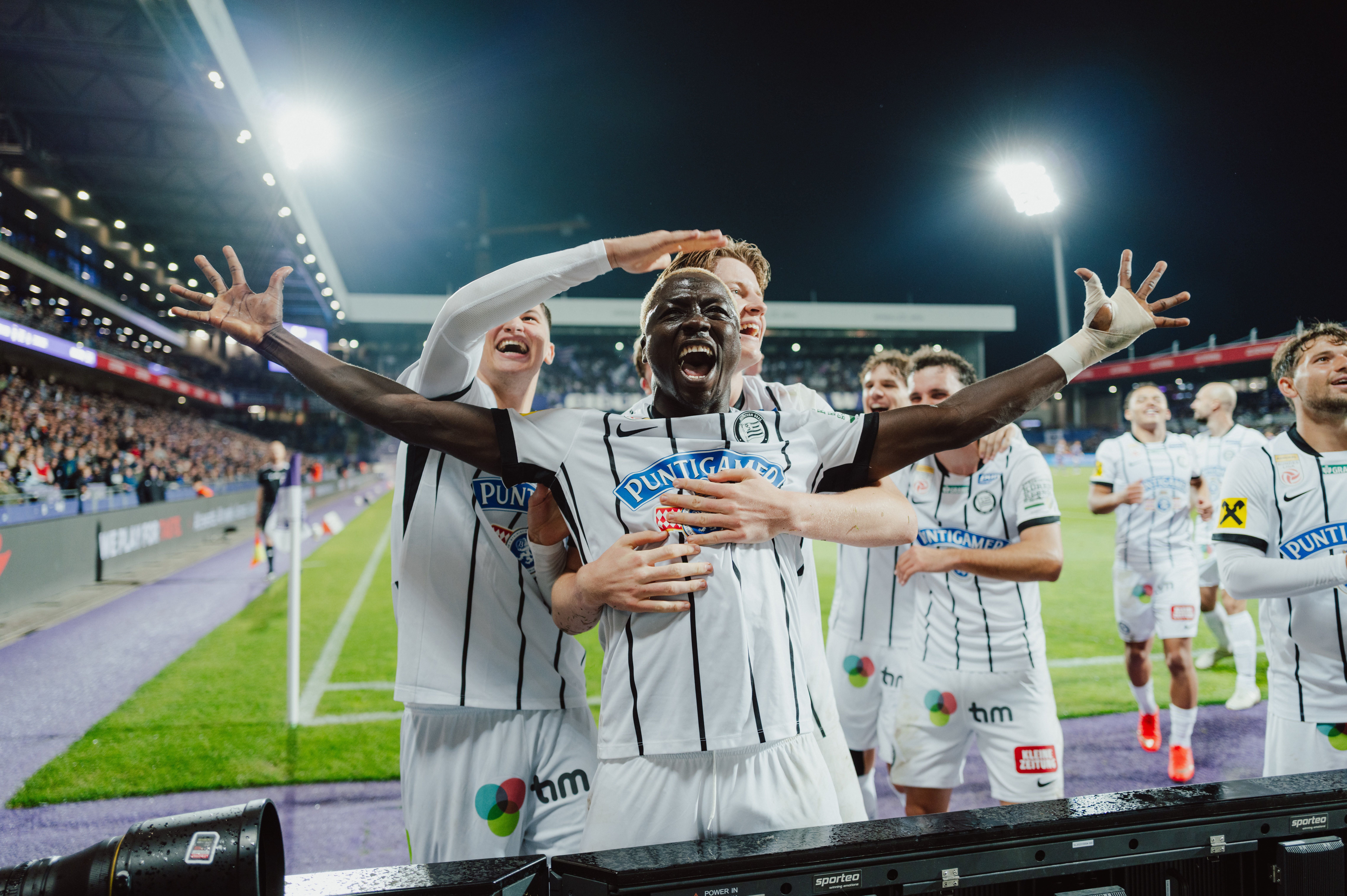 Jubelnde Spieler von SK Sturm Graz feiern ein Tor bei einem Fußballspiel im Stadion.
