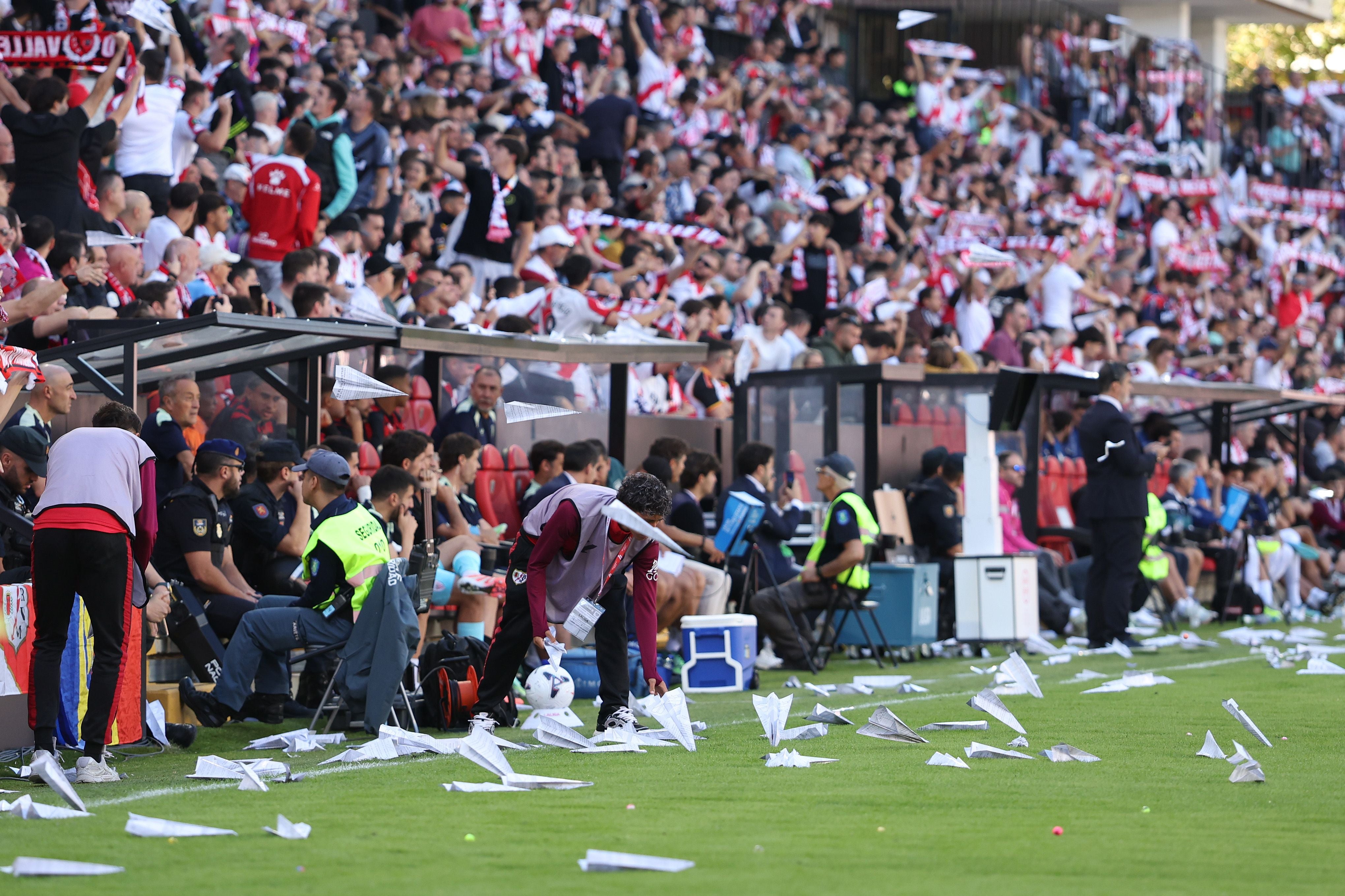 Viele Papierflieger liegen auf dem Spielfeld, im Hintergrund jubelnde Fußballfans im Stadion.