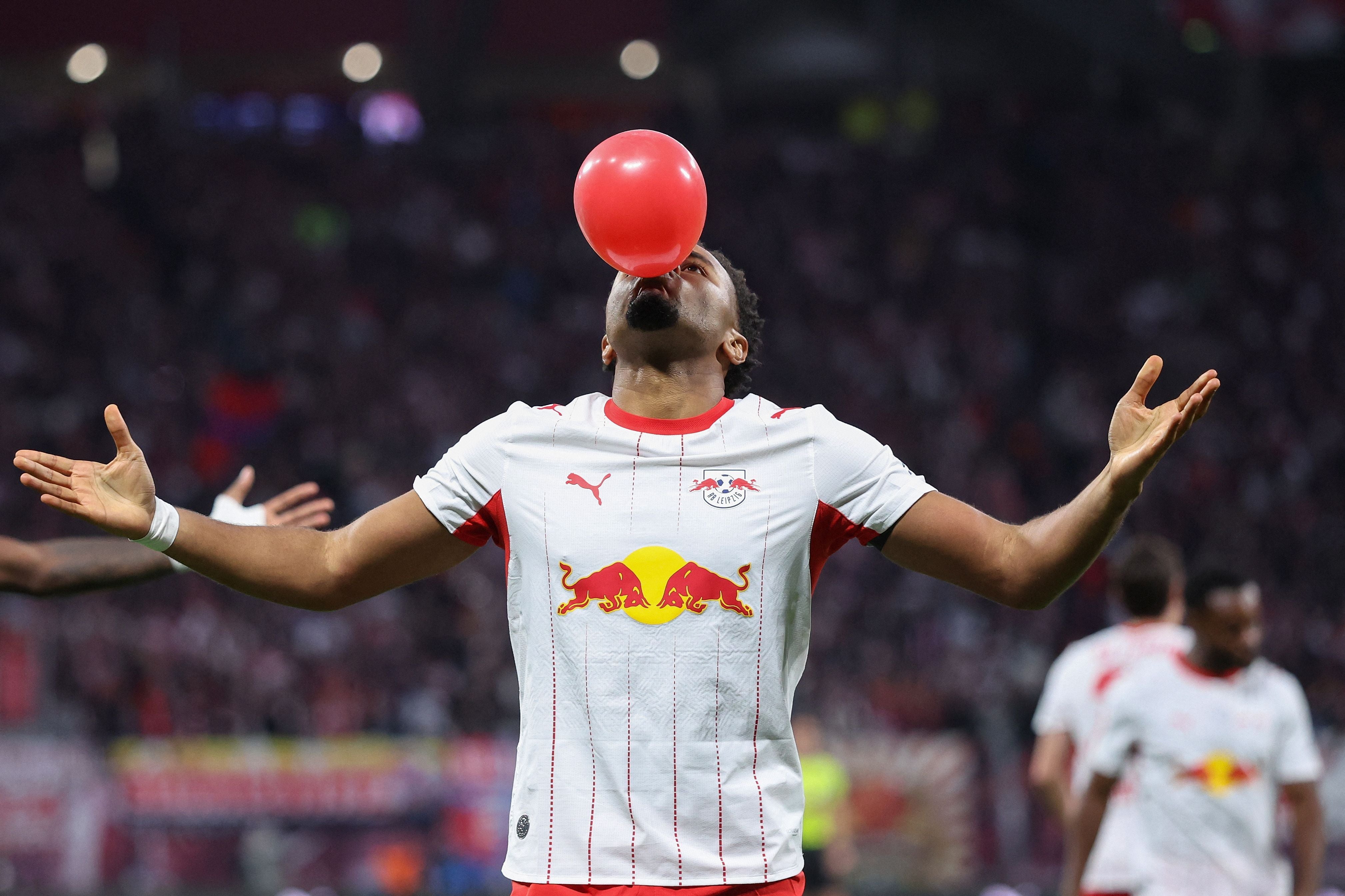 Ein Fußballspieler von RB Leipzig feiert mit einem roten Ballon auf dem Spielfeld.