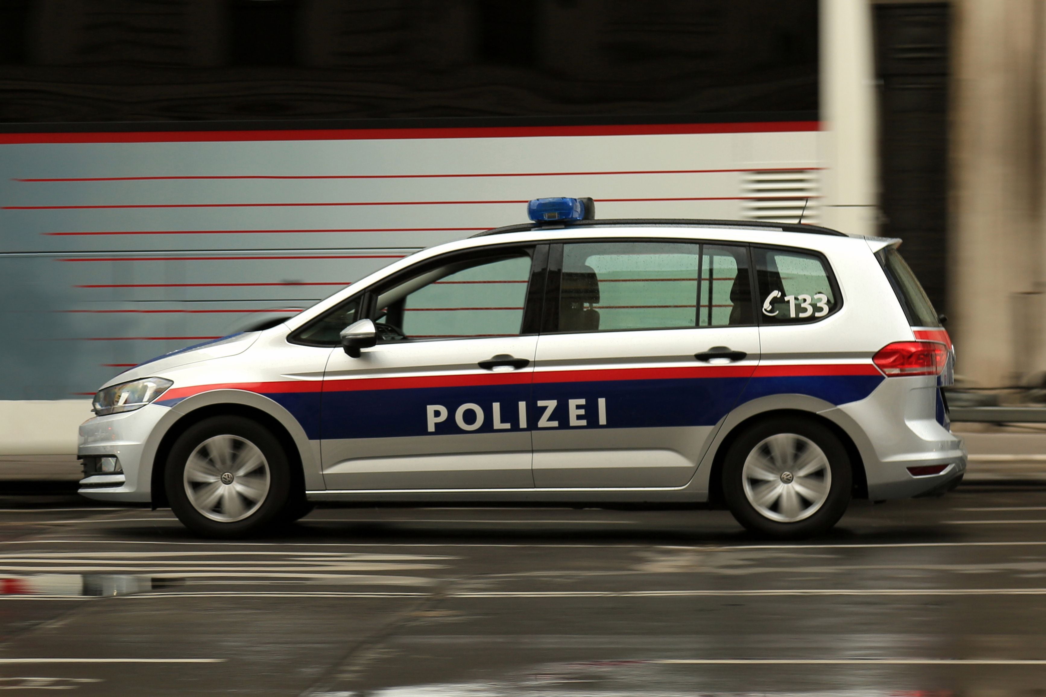 Ein österreichisches Polizeiauto fährt schnell durch eine Stadtstraße.