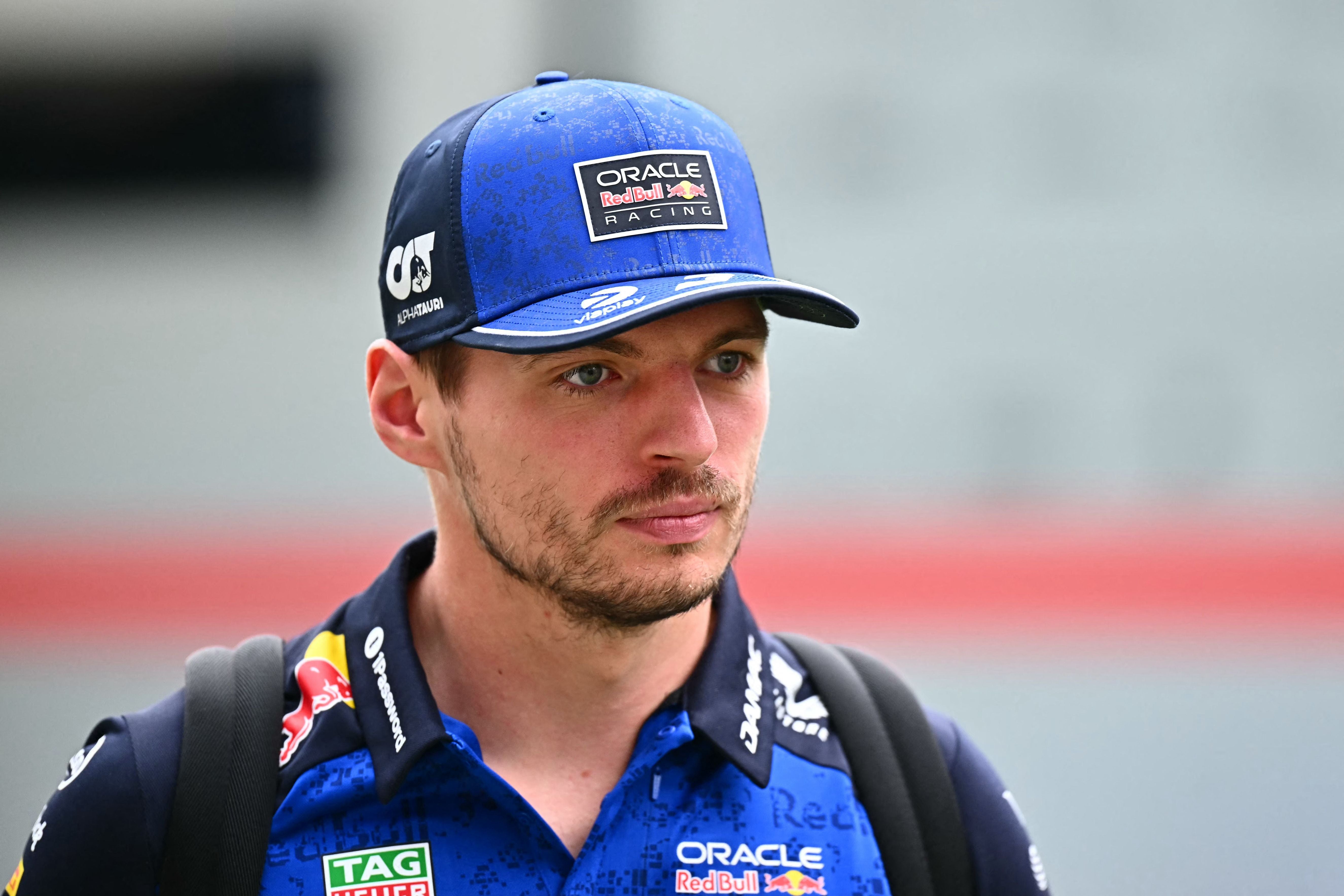 Ein Mann in Red Bull Racing Kleidung und blauer Kappe läuft durch ein Formel-1-Fahrerlager.