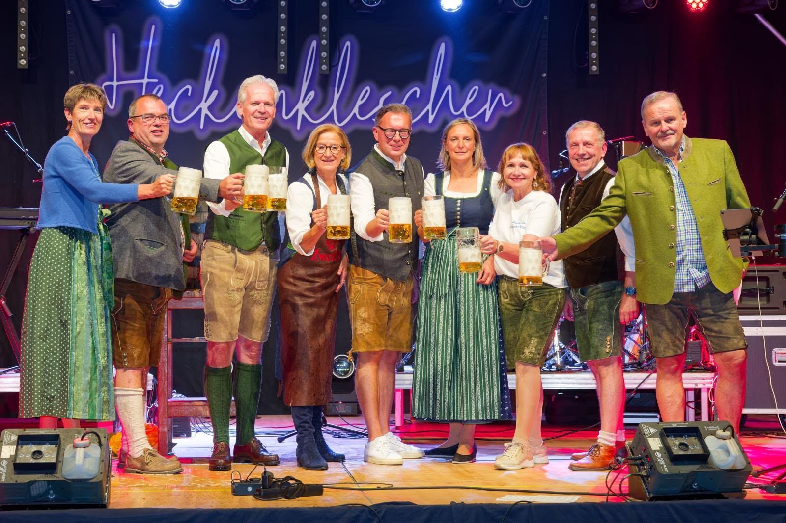 Eine Gruppe von Menschen in Tracht hält Bierkrüge auf der Bühne beim Oktoberfest Waidhofen.
