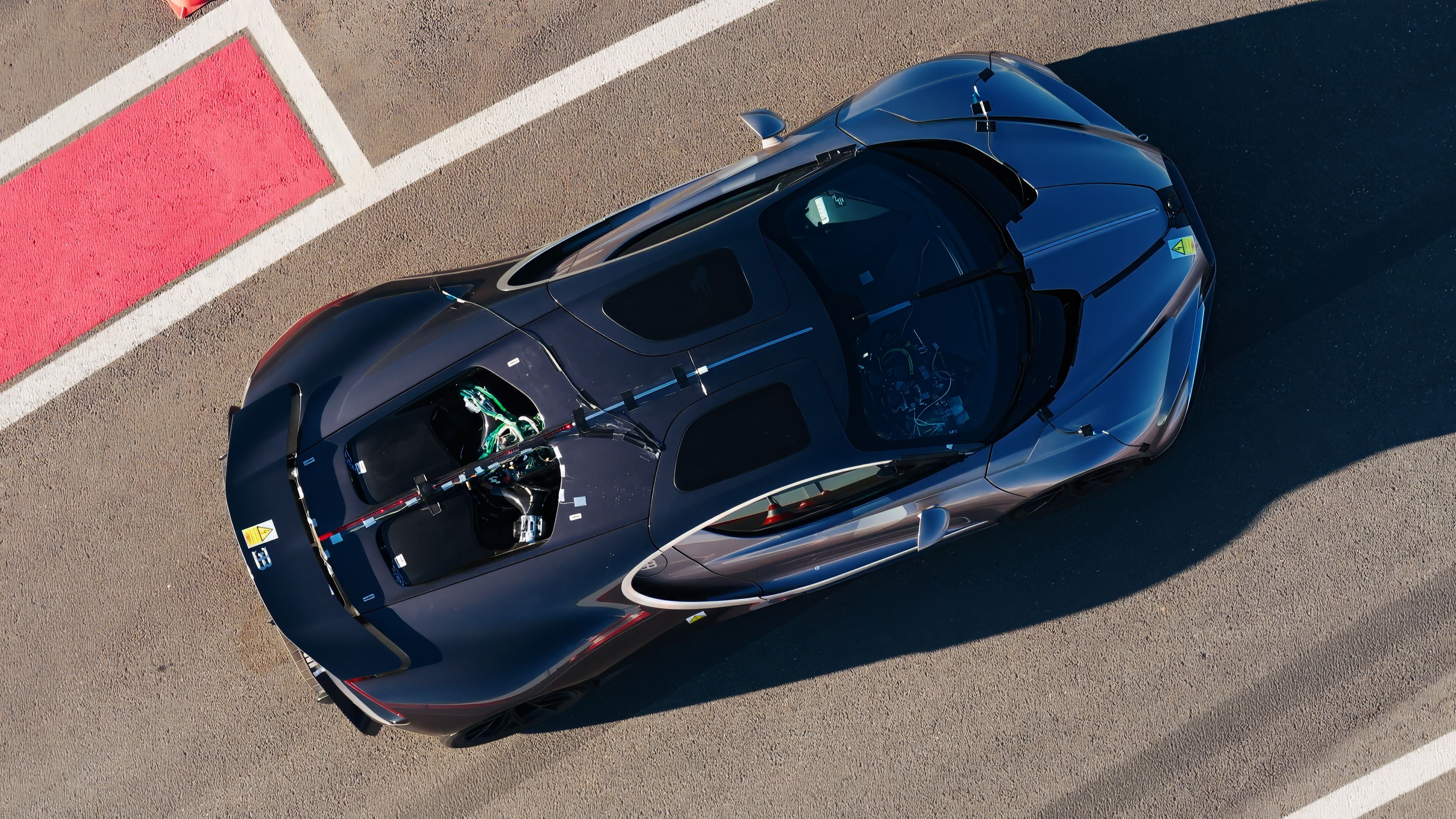 Draufsicht auf einen schwarzen Bugatti Tourbillon auf einer Rennstrecke.