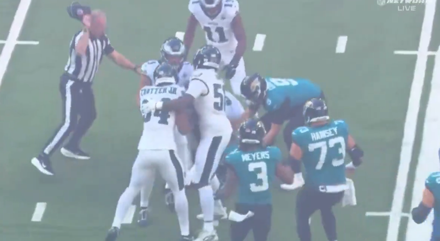 NFL-Spieler und ein Schiedsrichter während eines Spiels in London auf dem Spielfeld.