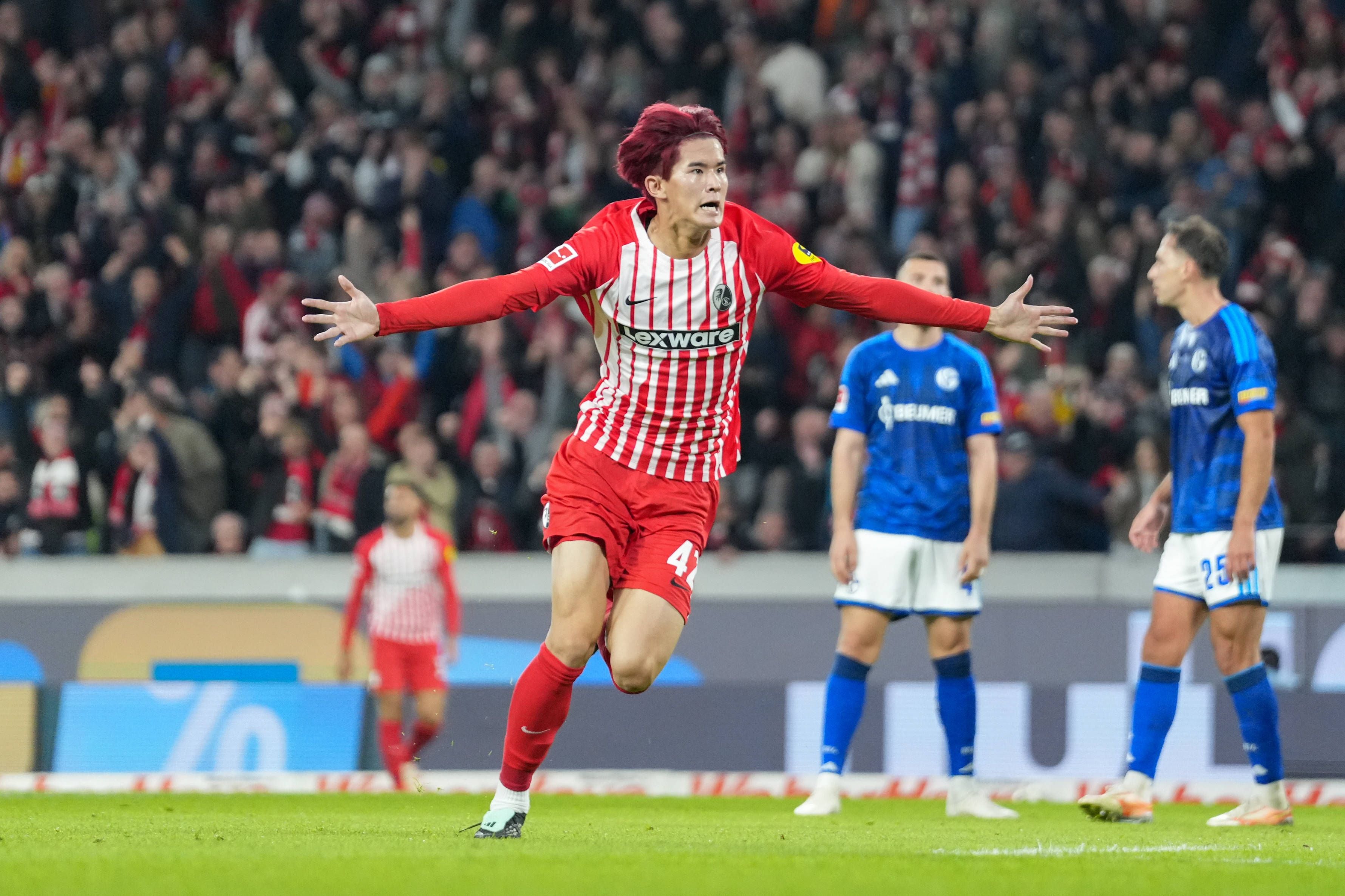 Ein Fußballspieler des SC Freiburg jubelt mit ausgebreiteten Armen nach einem Tor, im Stadion.