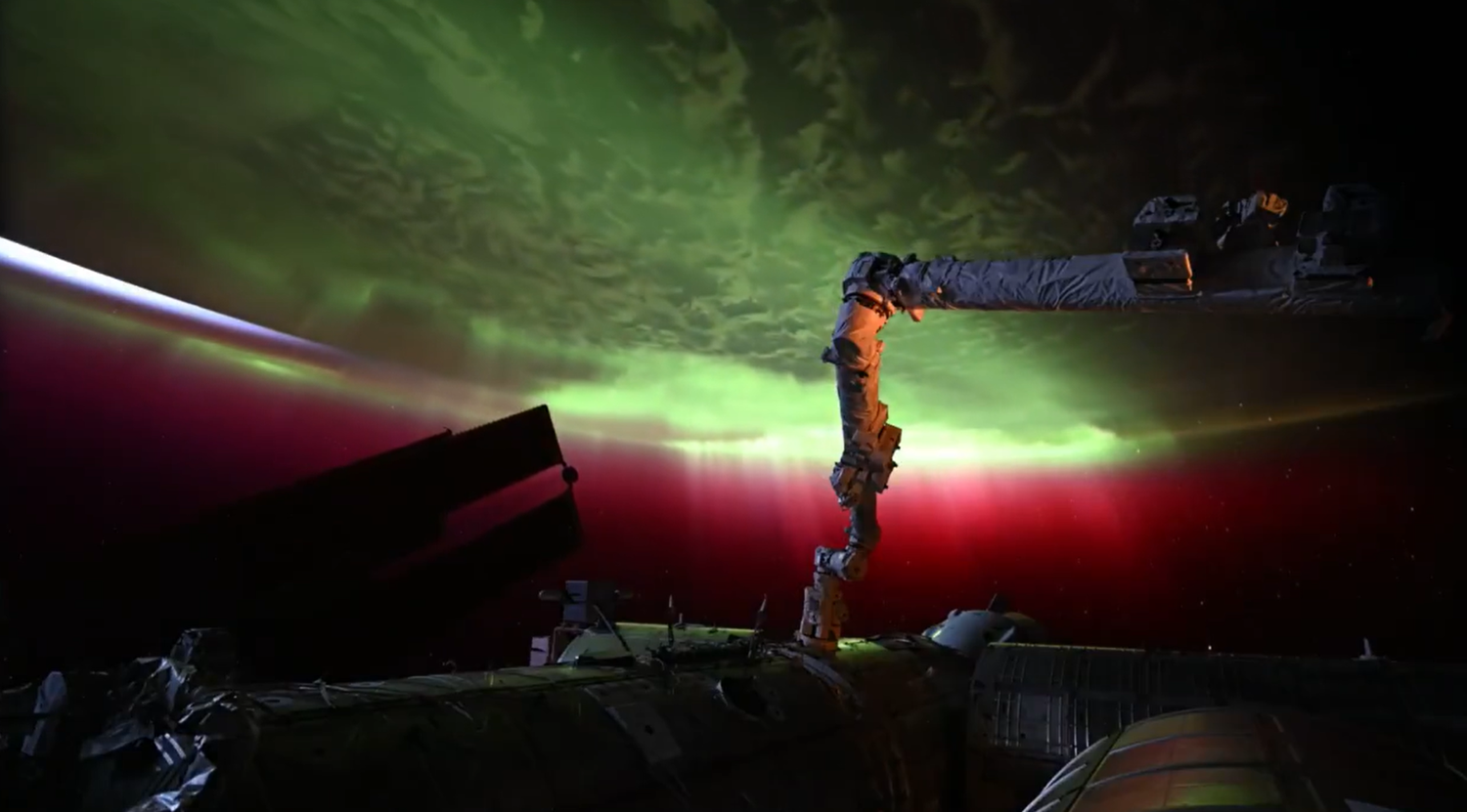 Grüne und rote Polarlichter leuchten über der ISS im Weltall.