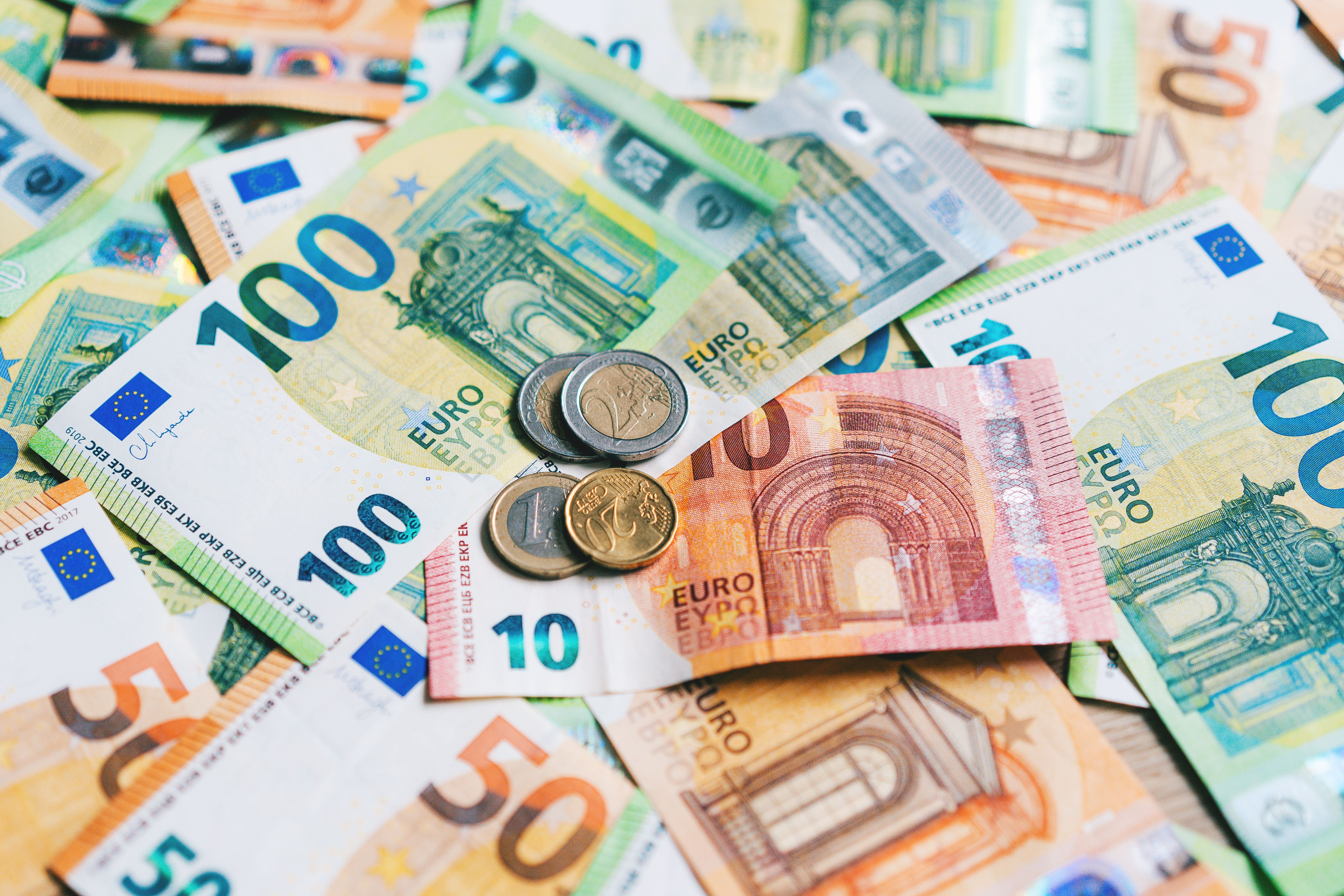 Verschiedene Euro-Banknoten und -Münzen liegen verstreut auf einer Fläche.