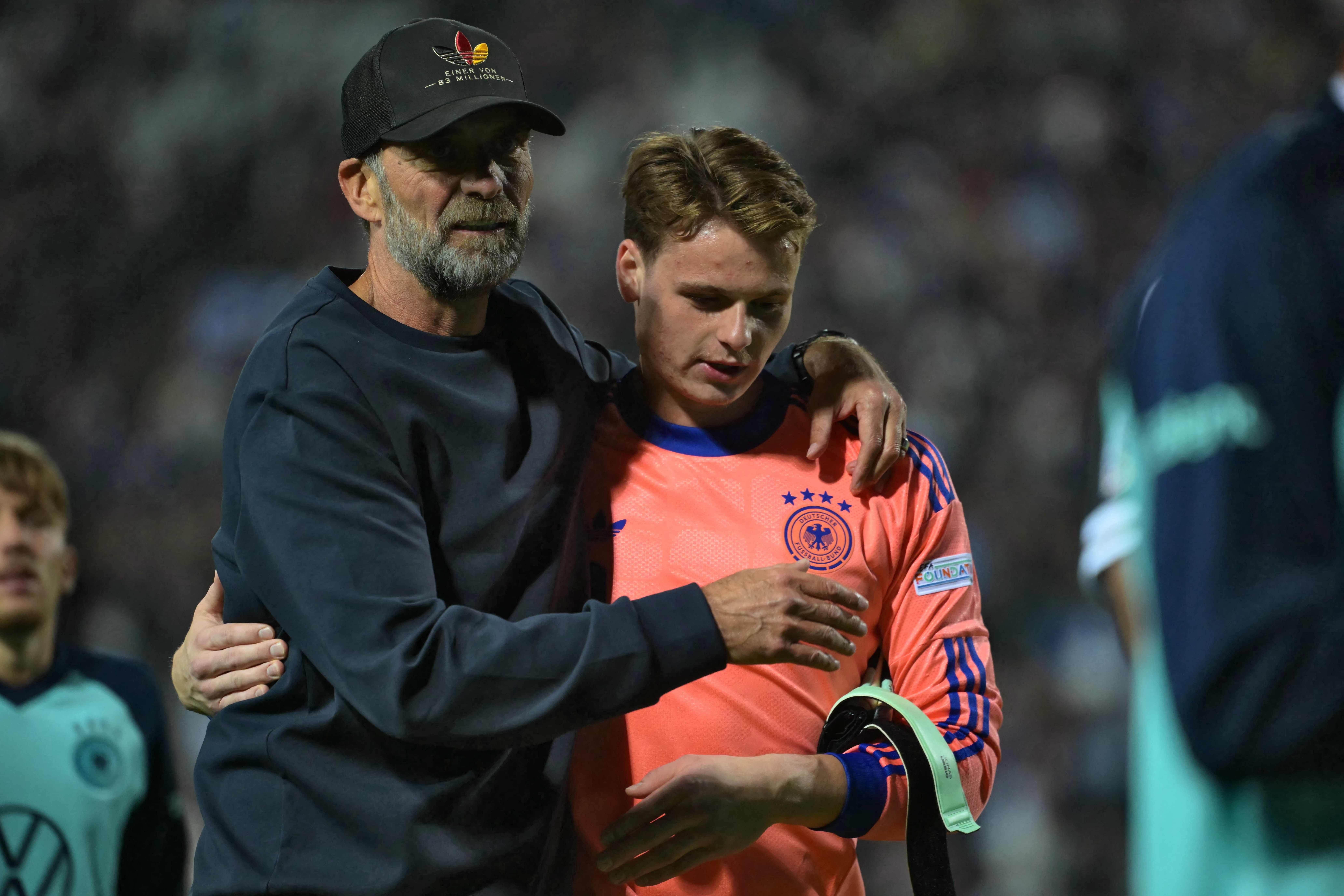 Ein Trainer tröstet einen deutschen Torwart nach einem Fußballspiel im Stadion.