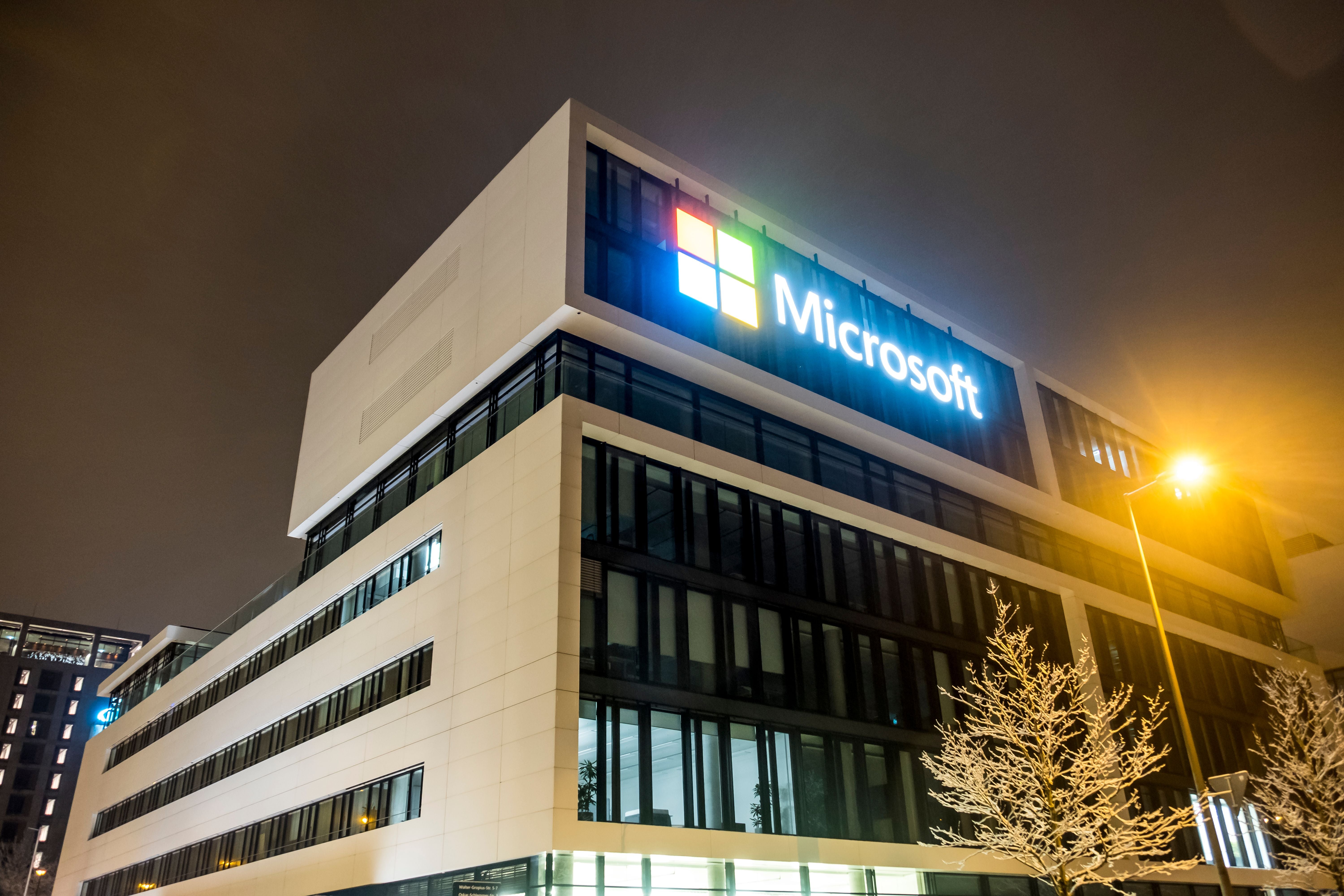 Modernes Microsoft-Gebäude in München bei Nacht, mit beleuchtetem Logo auf der Fassade.