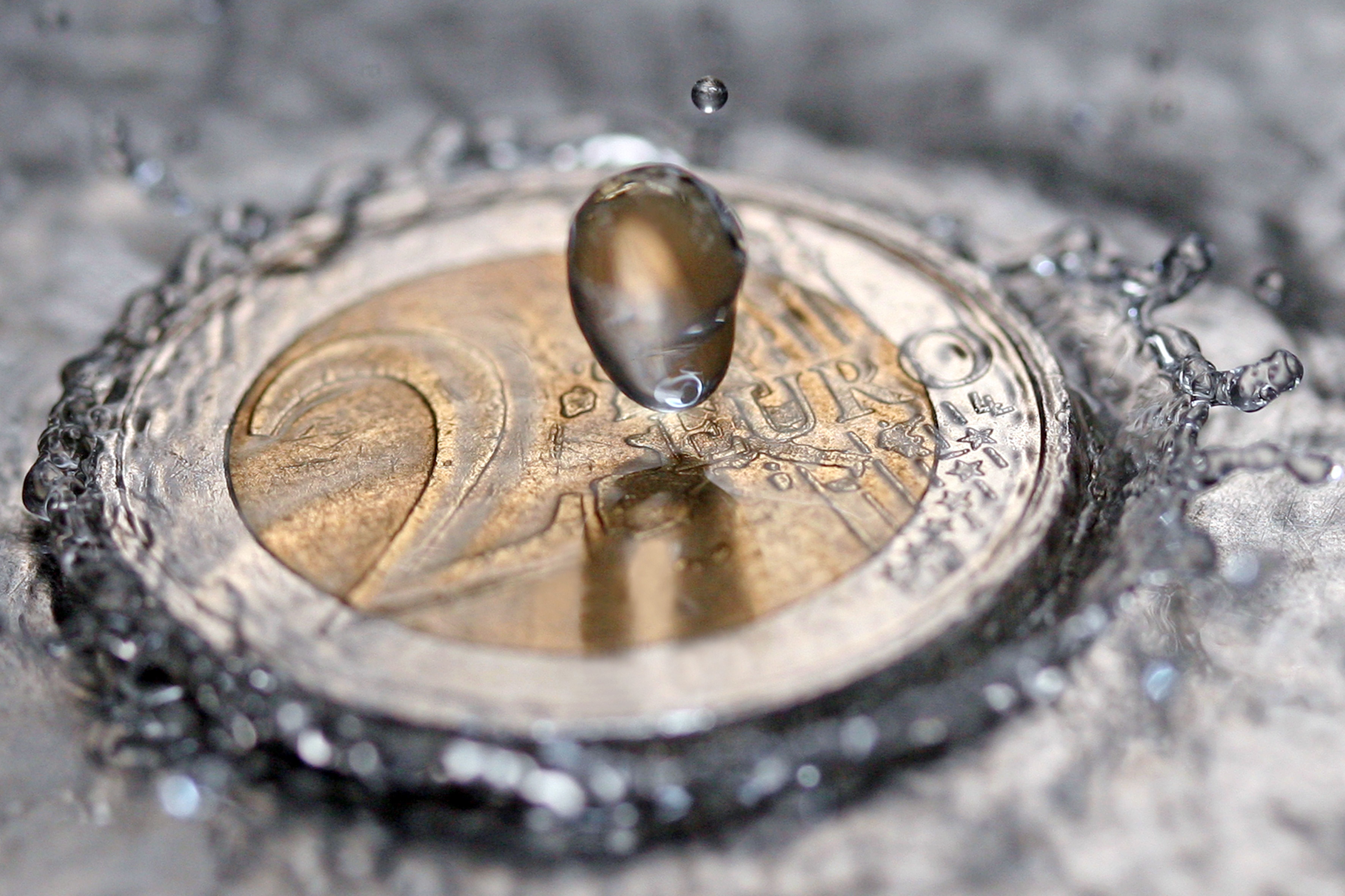 Eine fallende Wassertropfen trifft eine Zwei-Euro-Münze und erzeugt eine Spritzkrone.