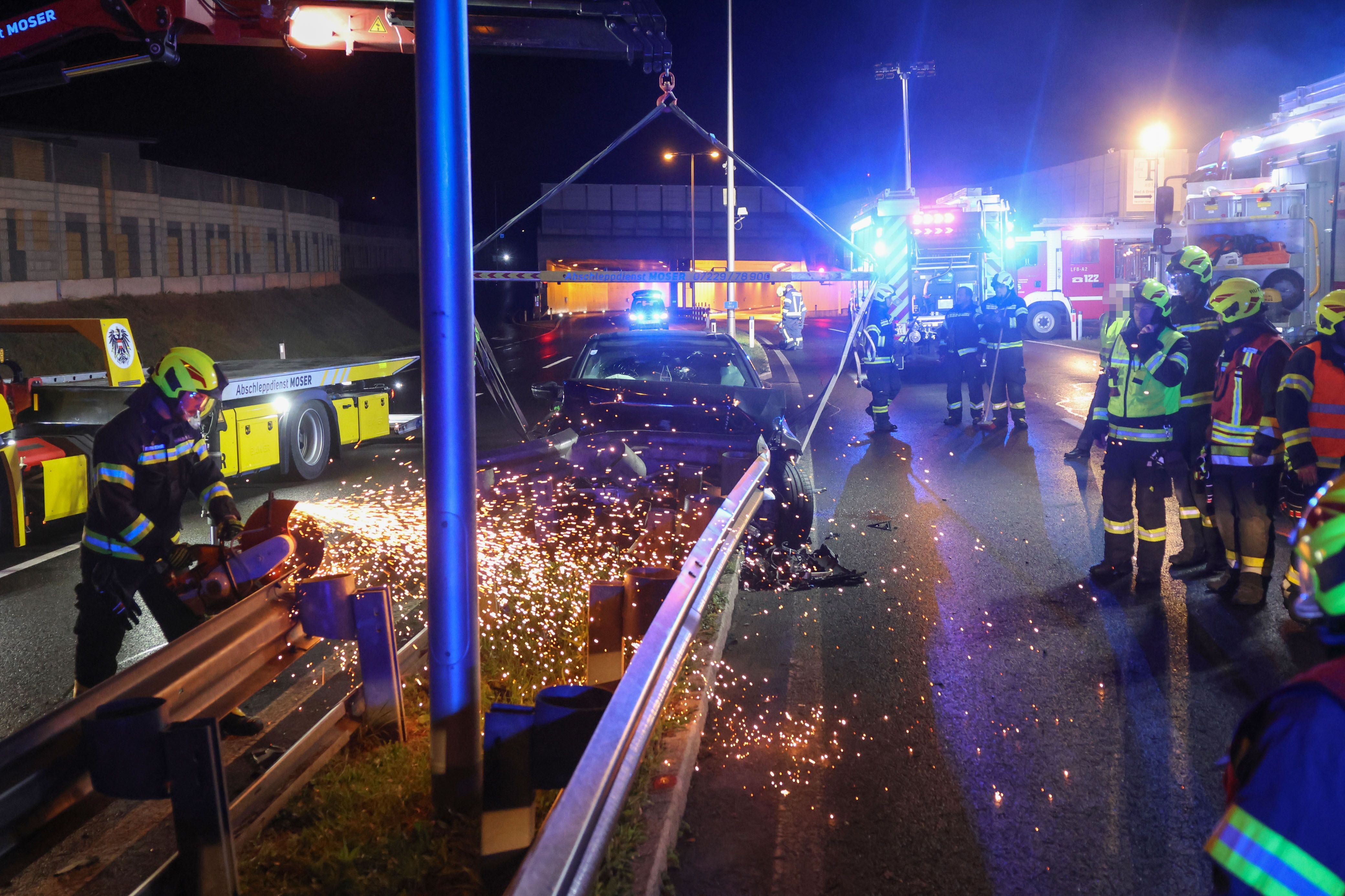 Feuerwehrleute befreien nachts ein Unfallauto beim Tunnelneubau in Hörsching mit schwerem Gerät.