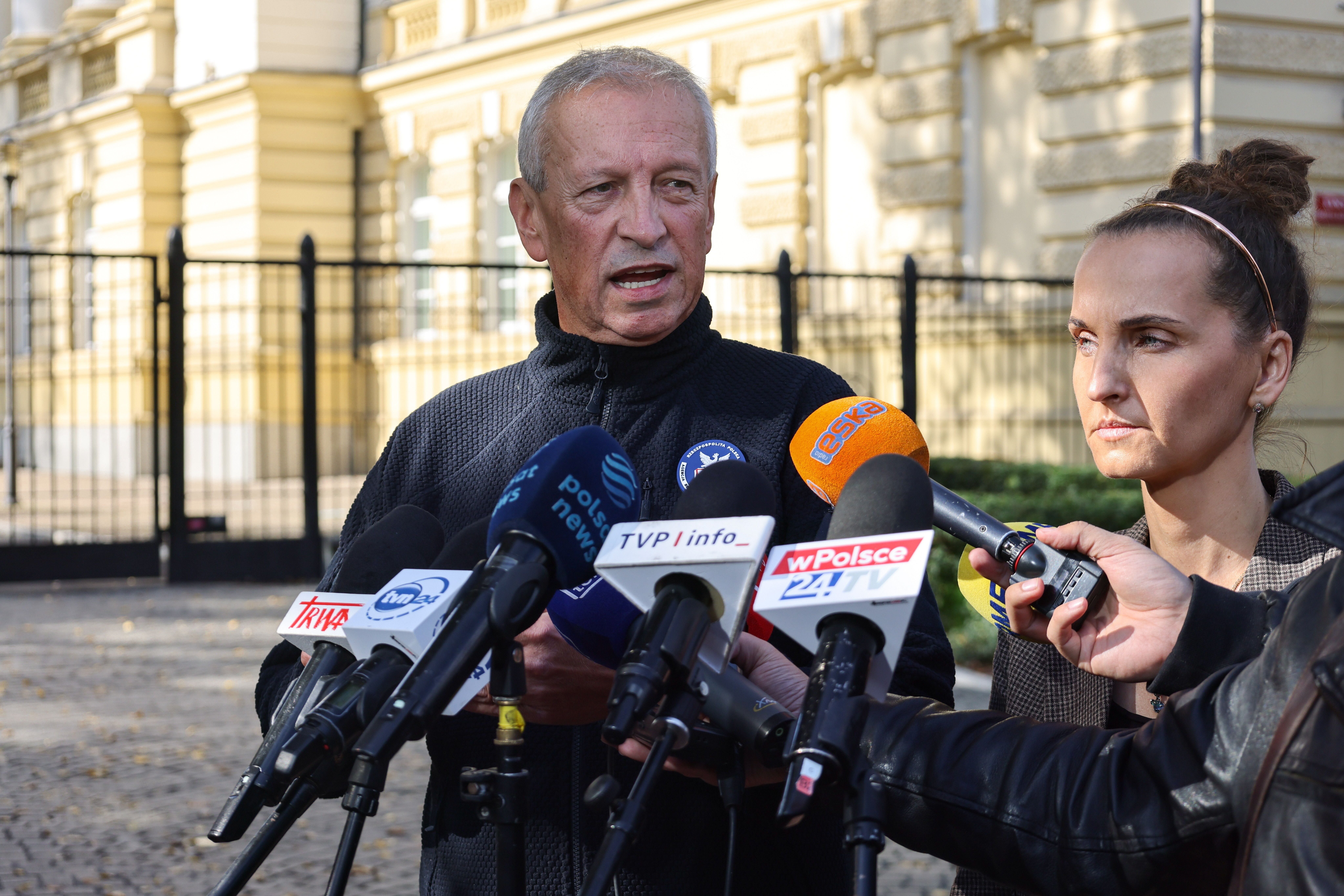 Ein Mann und eine Frau sprechen bei einer Pressekonferenz vor mehreren Mikrofonen im Freien.