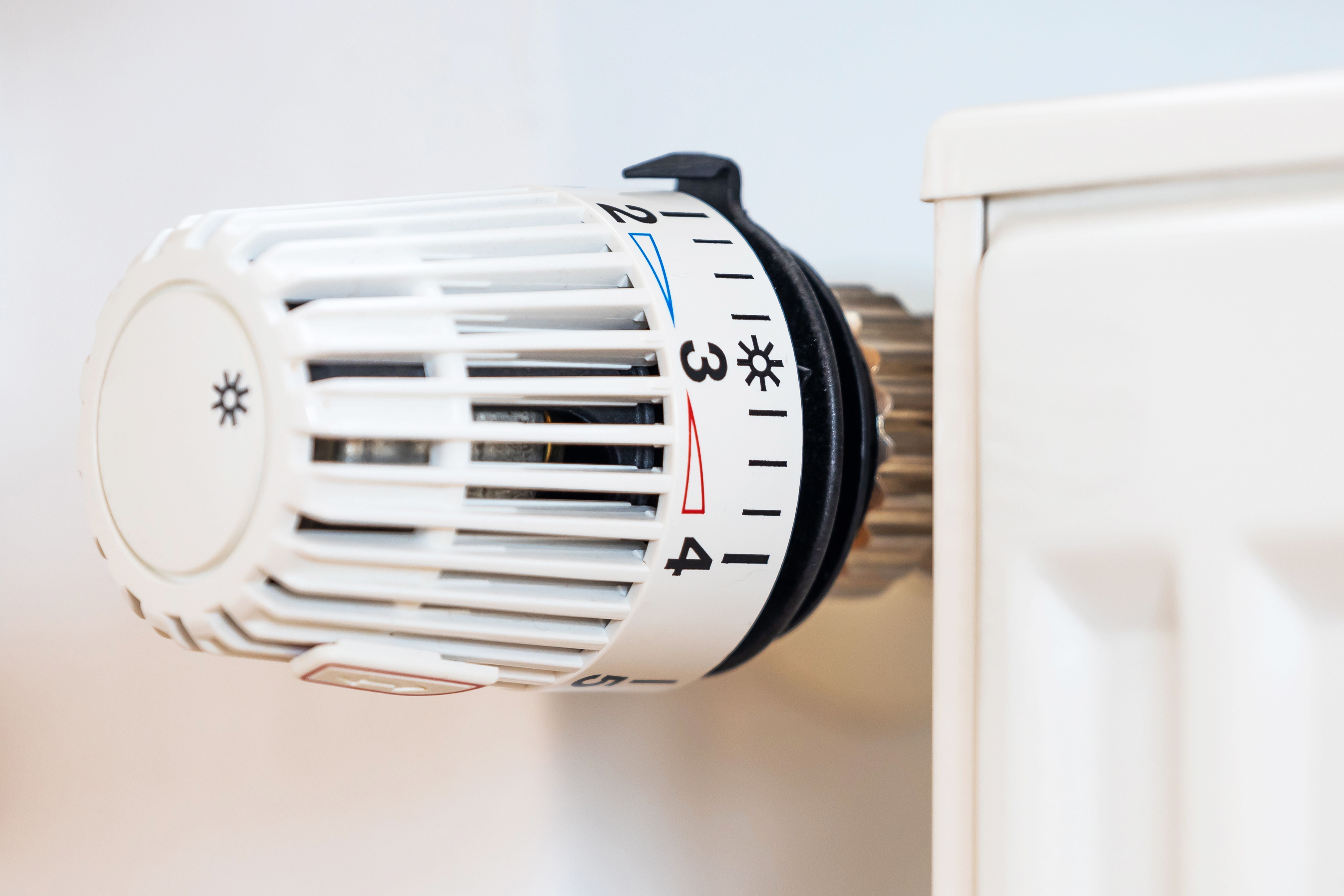 Nahaufnahme eines weißen Heizkörperthermostats mit Zahlen und Markierungen.