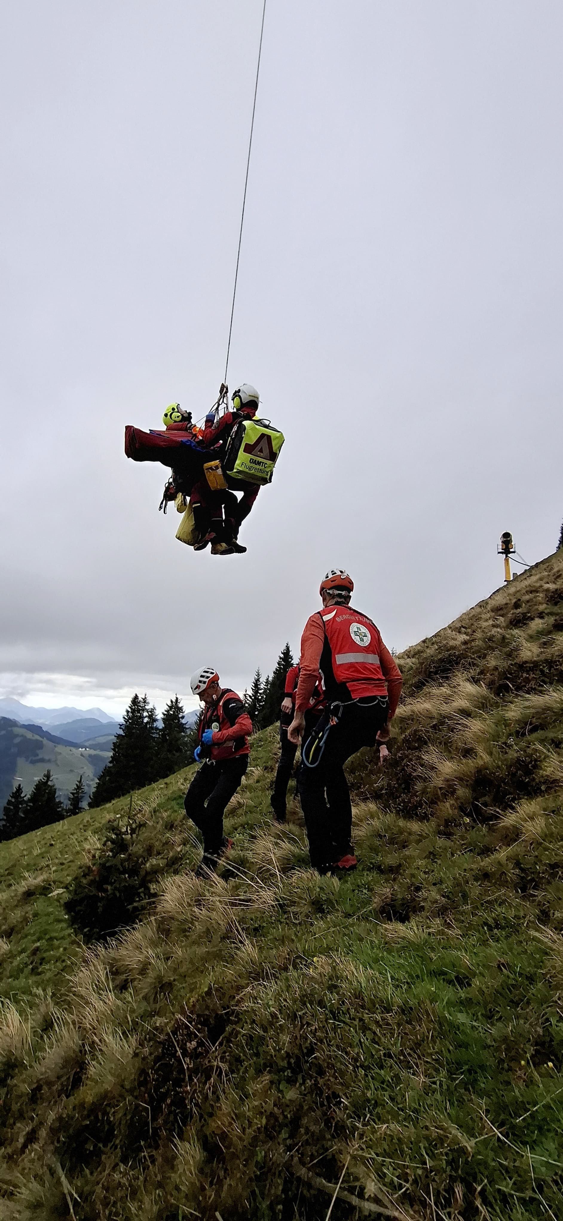 Bergretter führen eine Hubschrauberrettung an einem steilen Berghang durch.