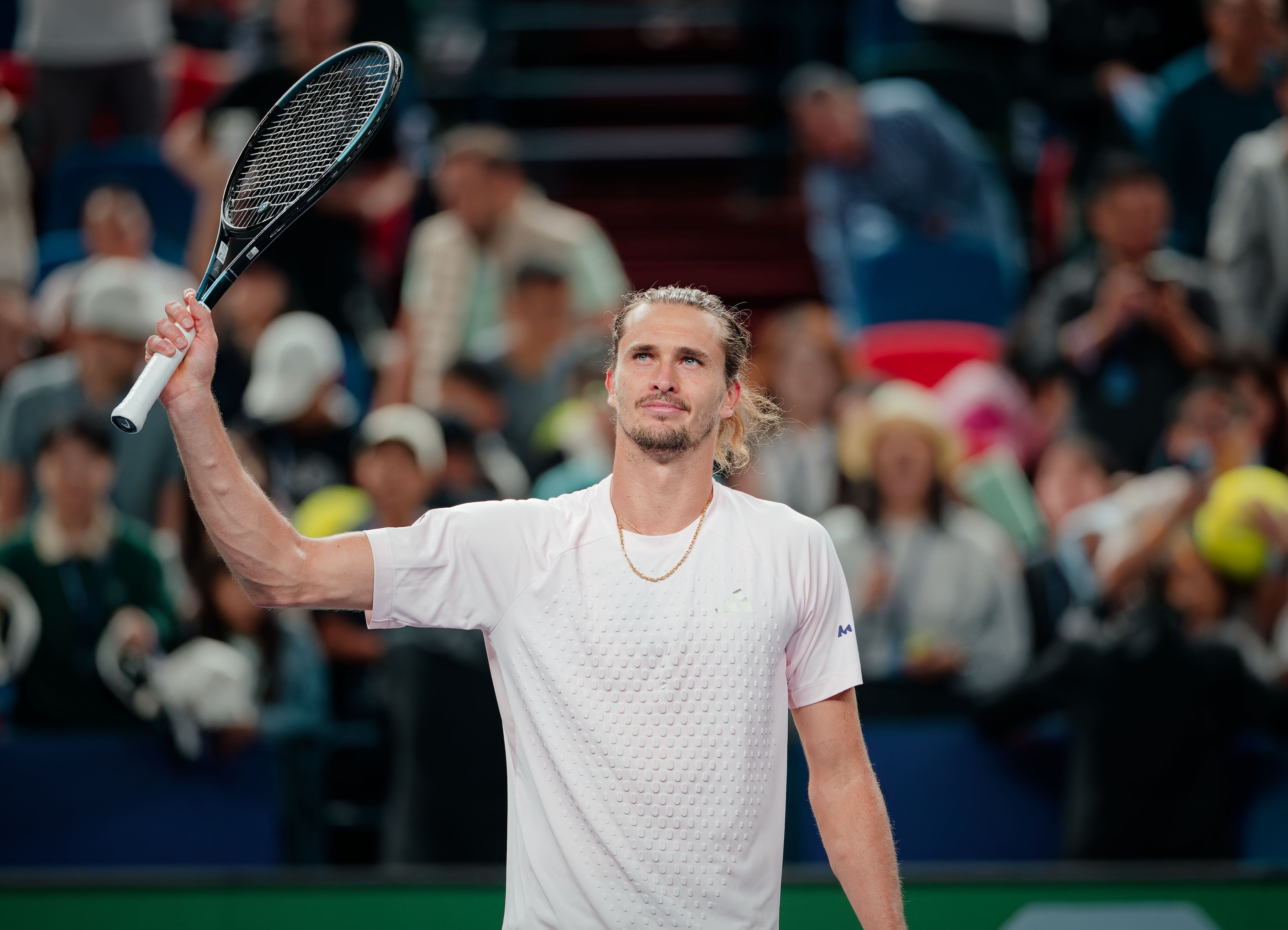 Ein Tennisspieler hebt seinen Schläger, im Hintergrund jubelndes Publikum.