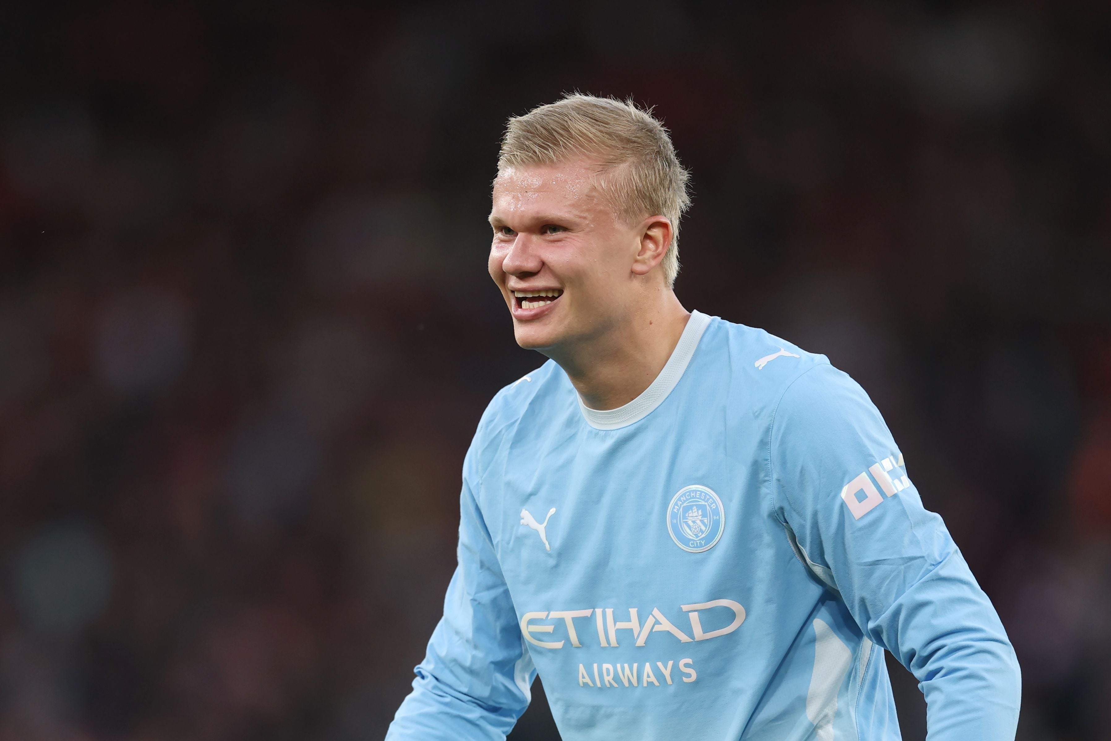 Porträt von Erling Haaland im hellblauen Trikot von Manchester City, der lächelnd zur Seite blickt.