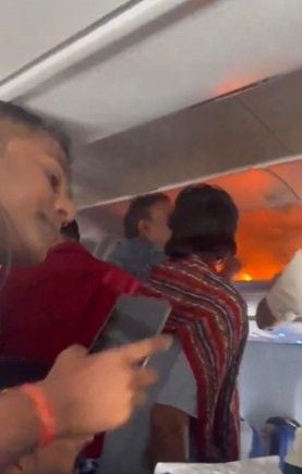 Flammen und Rauch im Passagierflugzeug, Menschen stehen im Gang.