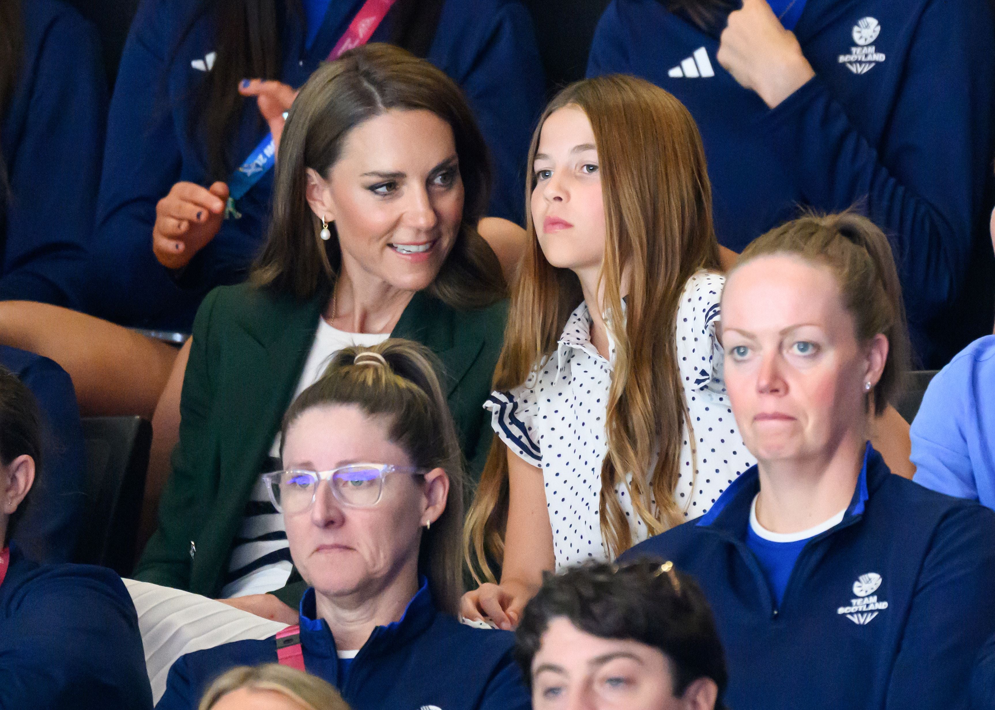 Eine Frau und ein Mädchen sitzen im Publikum bei einem Sportereignis, umgeben von Zuschauern.