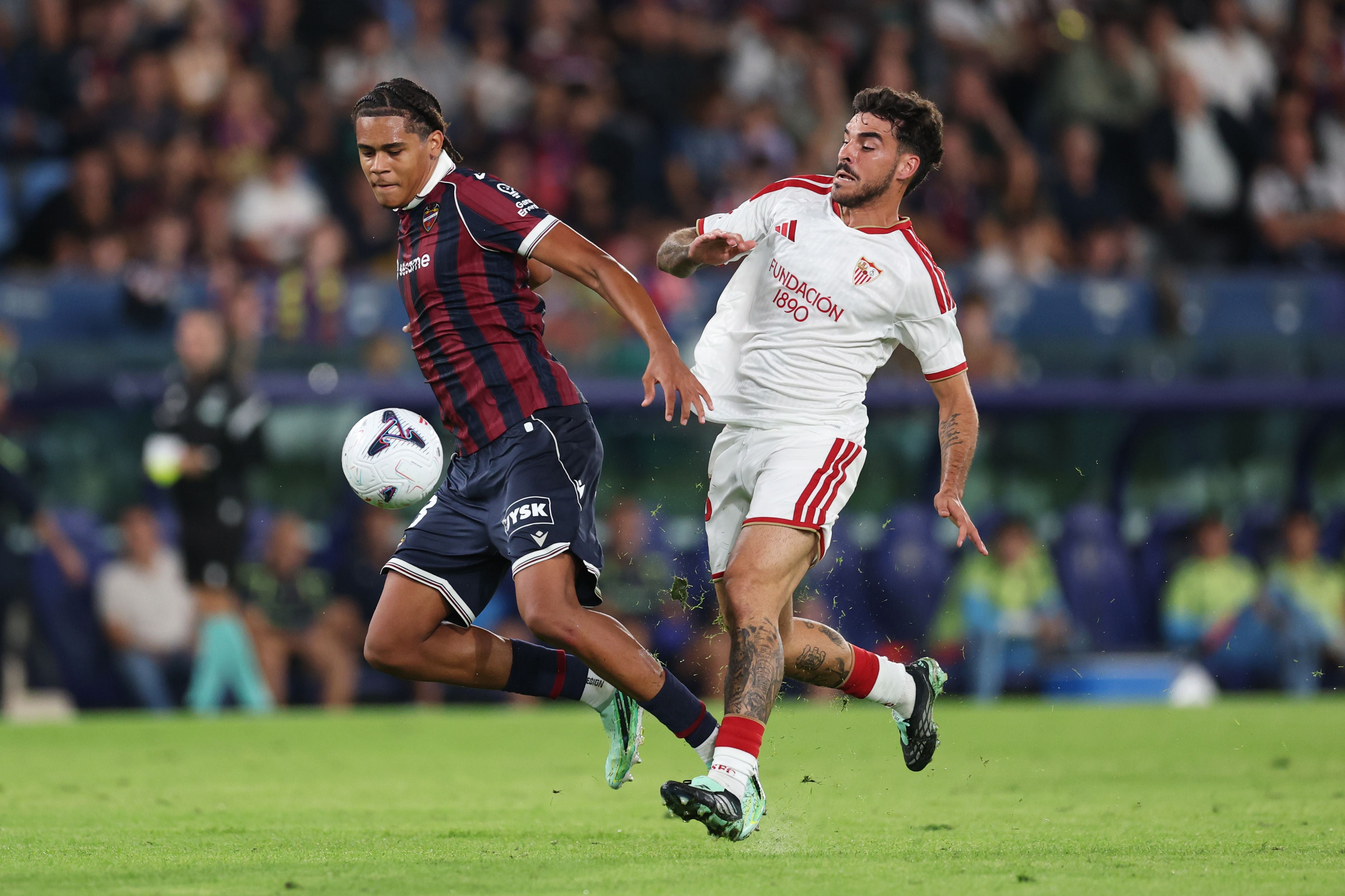 Ifeanyi Ndukwe von Levante kämpft im dunklen Trikot im Zweikampf gegen einen Gegenspieler des FC Sevilla im weißen Trikot um den Ball.