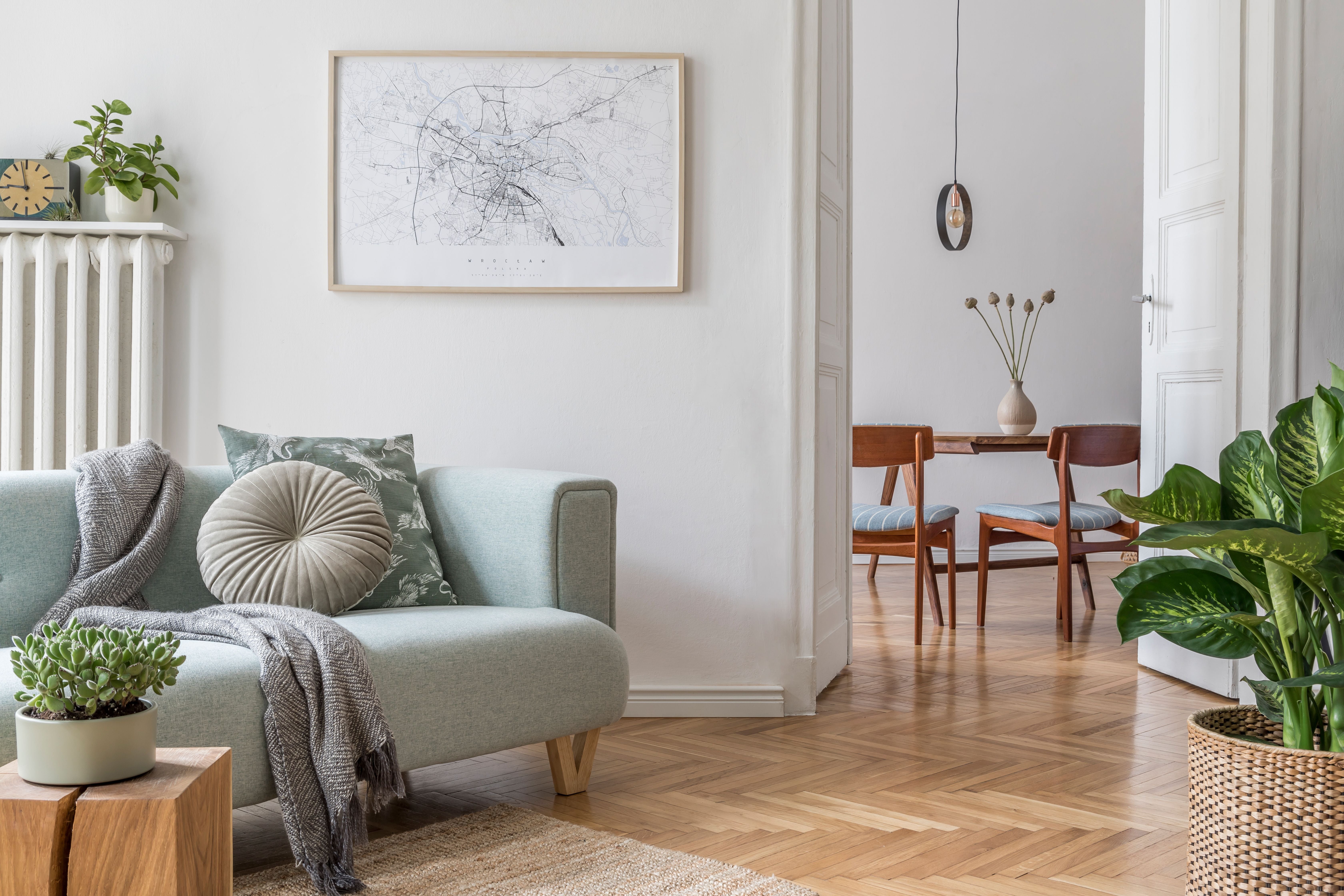 Helles Wohnzimmer im skandinavischen Stil mit Sofa, Pflanzen und Blick auf Essbereich.