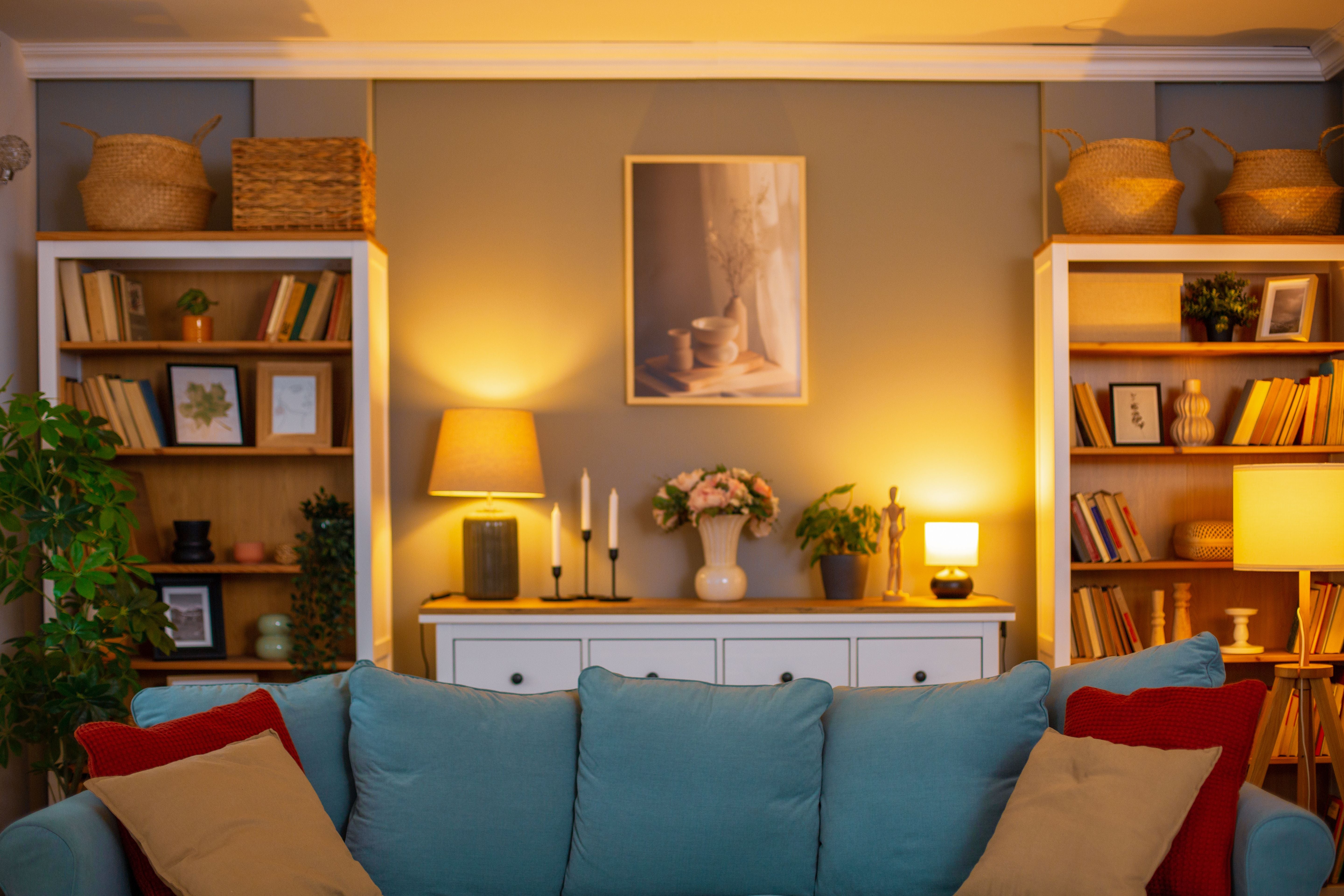 Gemütliches Wohnzimmer mit blauem Sofa, Bücherregalen, Lampen und stilvoller Dekoration.