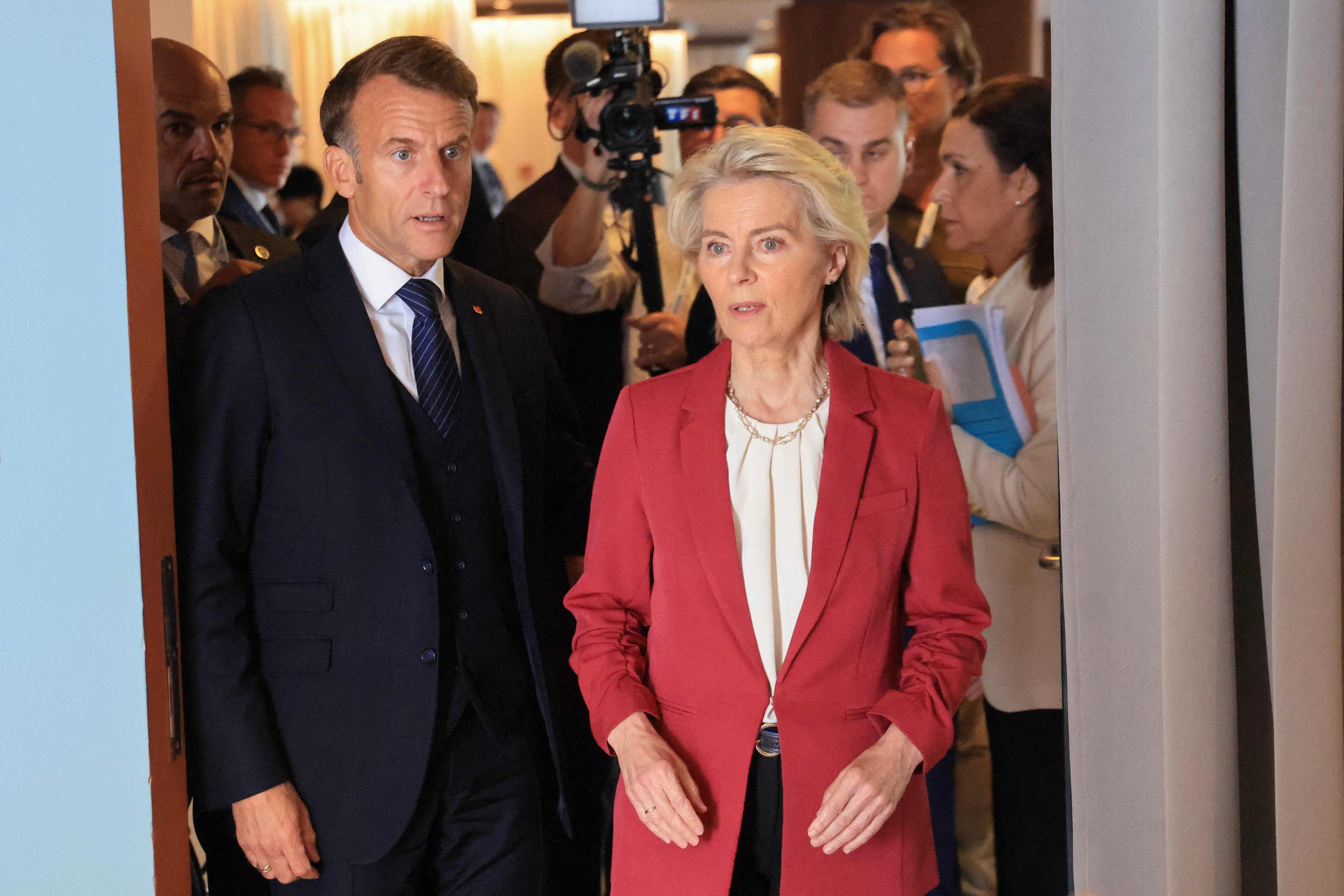 Ursula von der Leyen und Emmanuel Macron gehen gemeinsam durch einen Türrahmen, Menschen im Hintergrund.