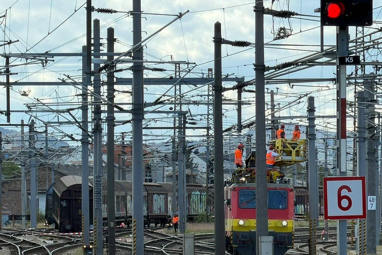 Mehrere Arbeiter reparieren Oberleitungen an einem ÖBB-Zug auf einem Gleisfeld mit Signalen.