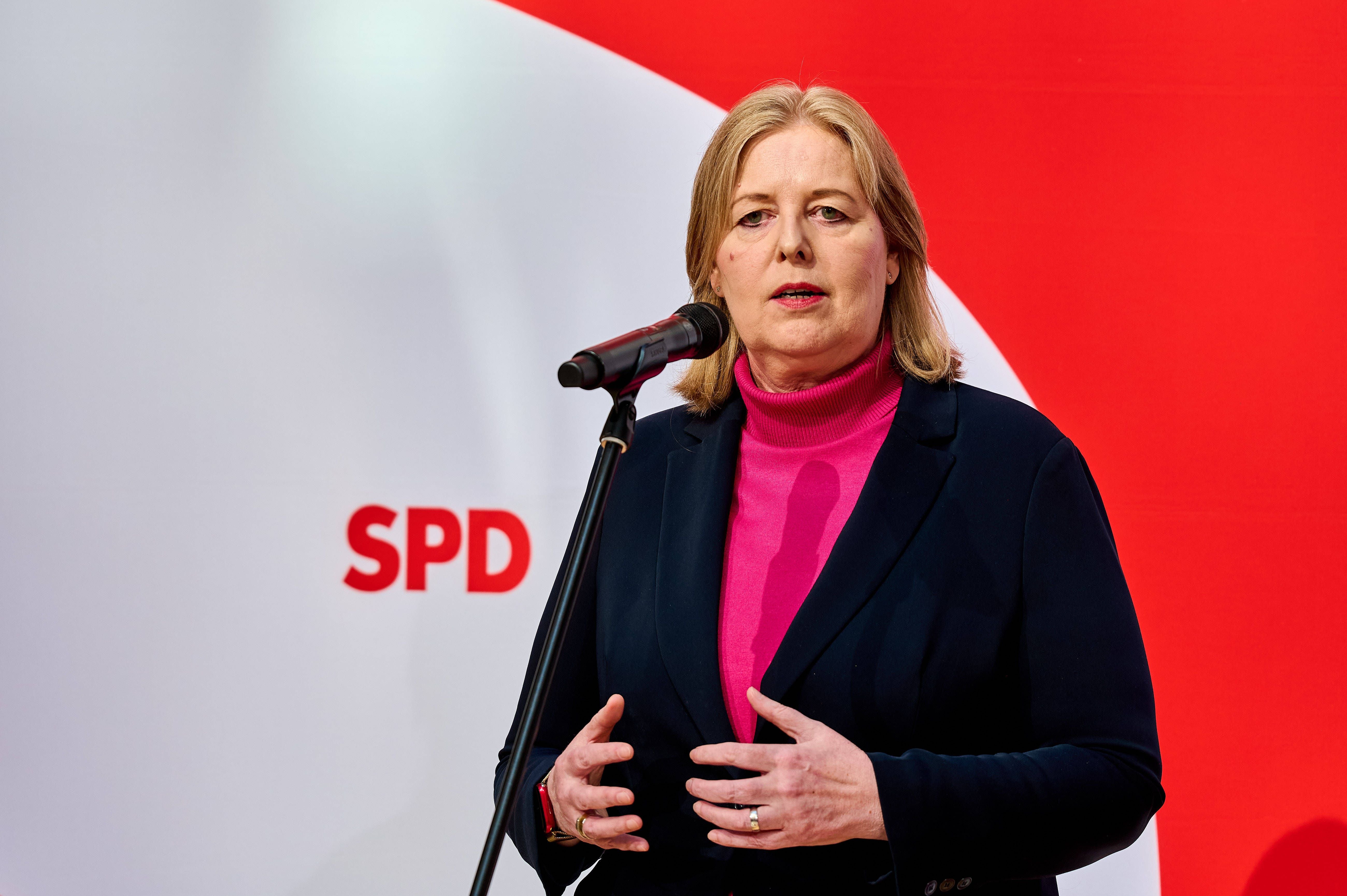 Frau spricht bei einer Pressekonferenz vor SPD-Logo und rotem Hintergrund ins Mikrofon.