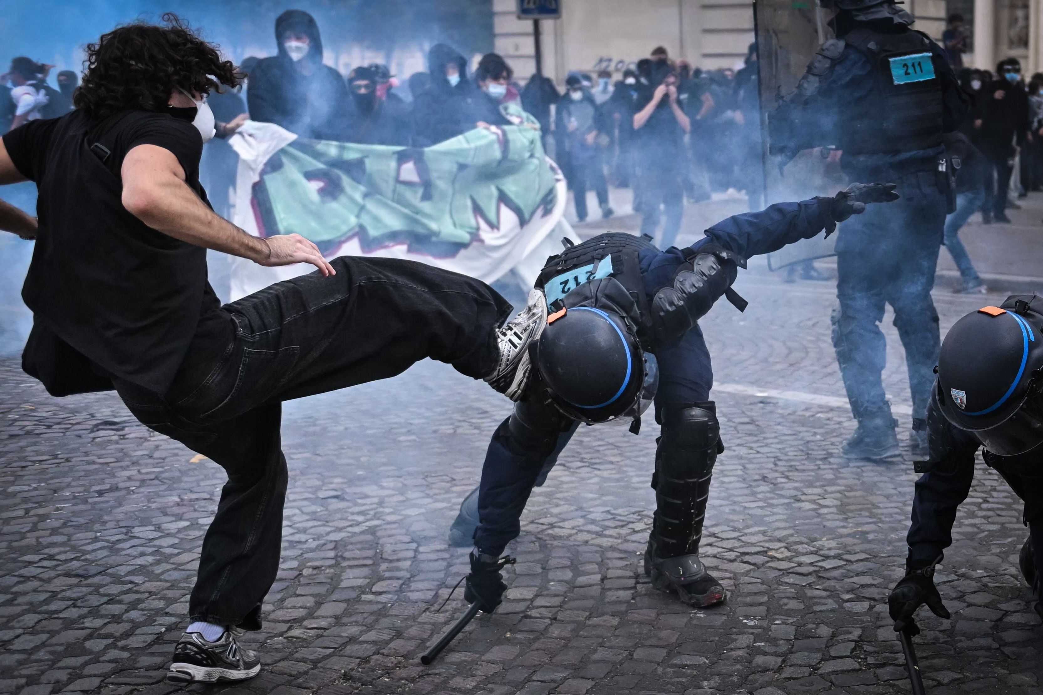 Ein Demonstrant tritt während einer Protestkundgebung in Paris gegen einen knienden Polizisten.