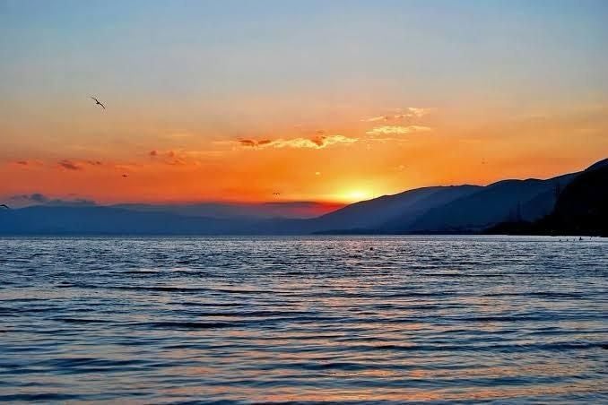 Sonnenuntergang über dem See Sevan in Armenien mit Bergen und ruhigem Wasser.