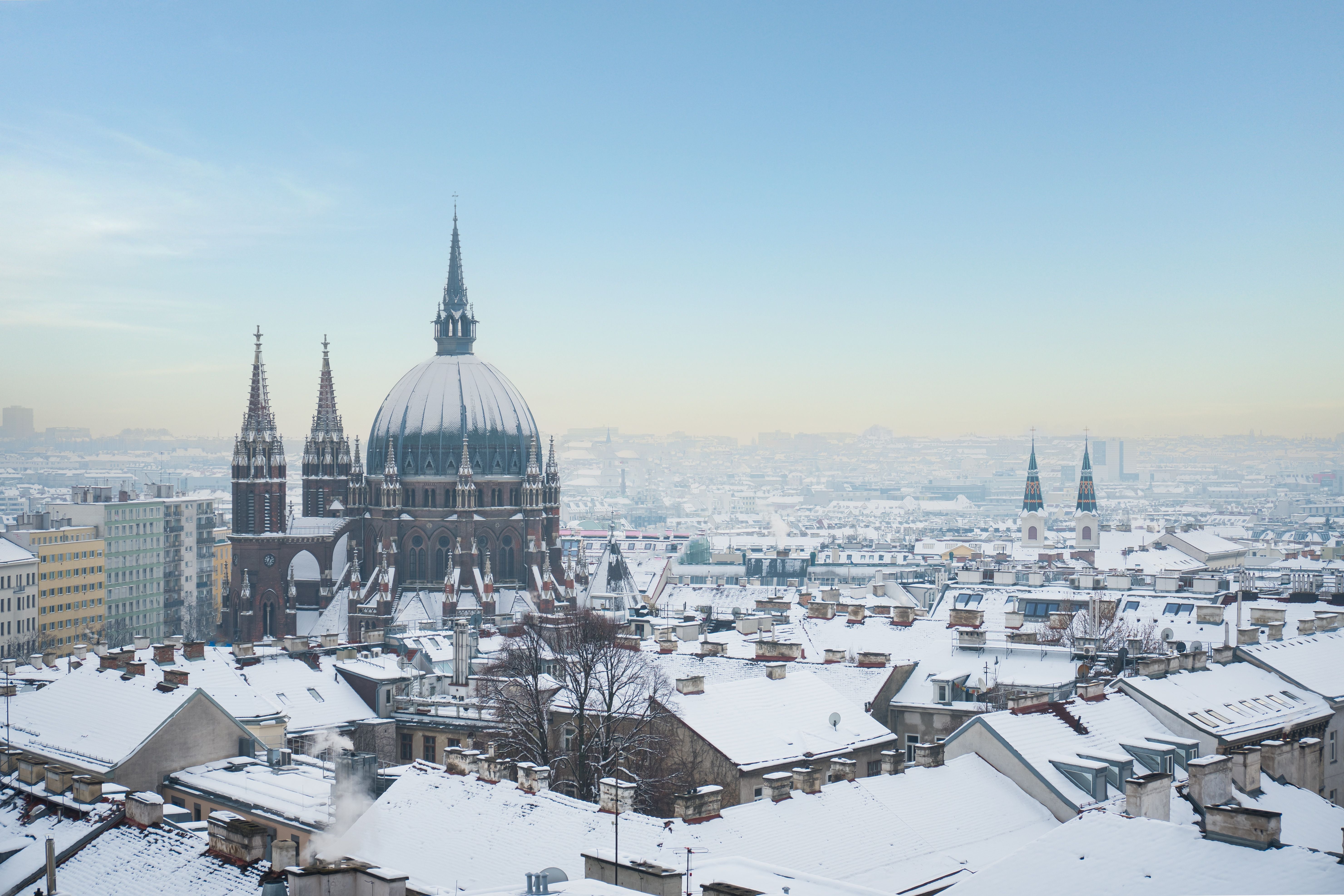 Winterliche Luftaufnahme der Kirche Maria vom Siege in Wien mit schneebedeckten Dächern.