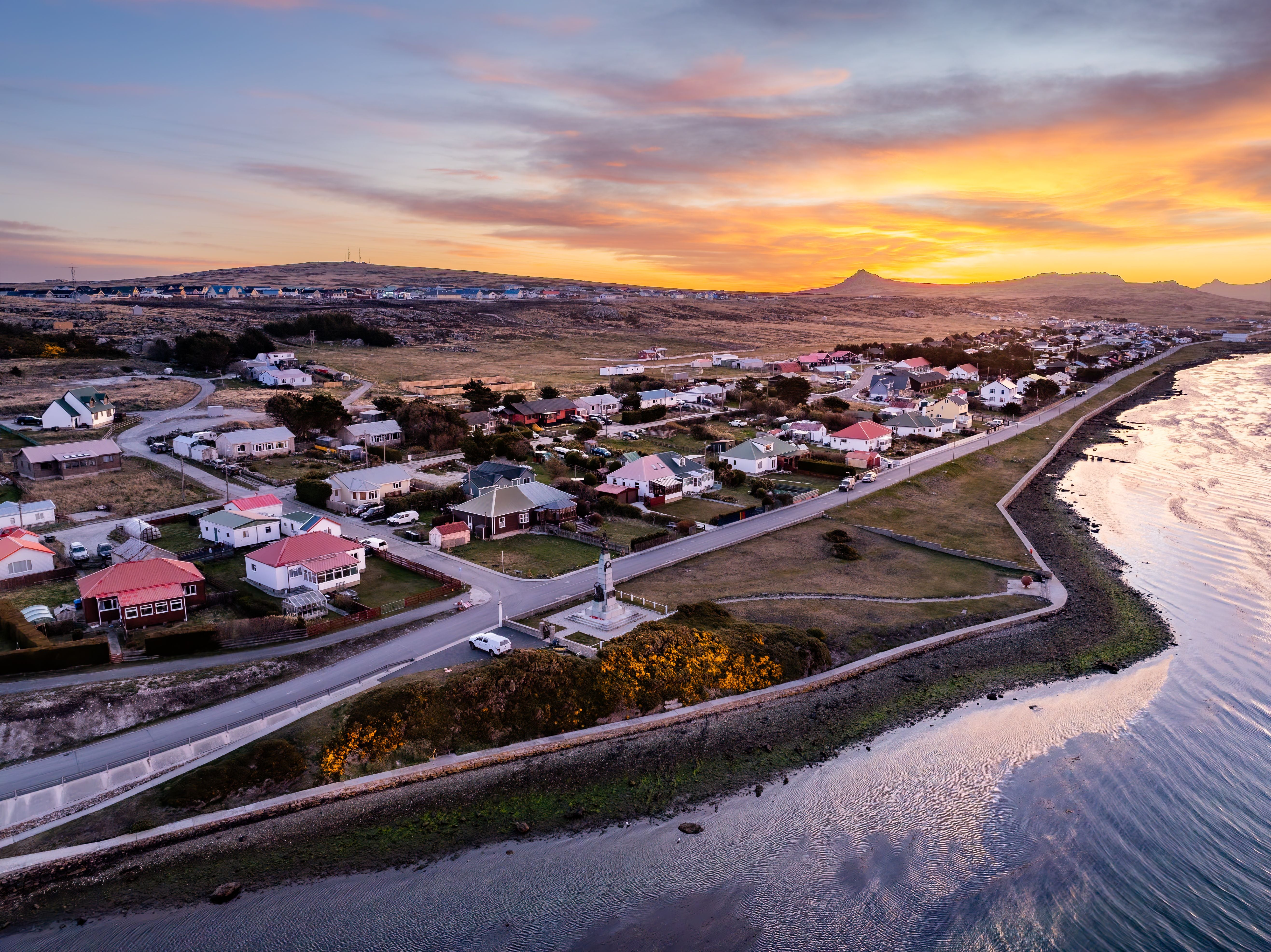 Sonnenuntergang über der Stadt Stanley auf den Falklandinseln mit Meer und bunten Häusern.