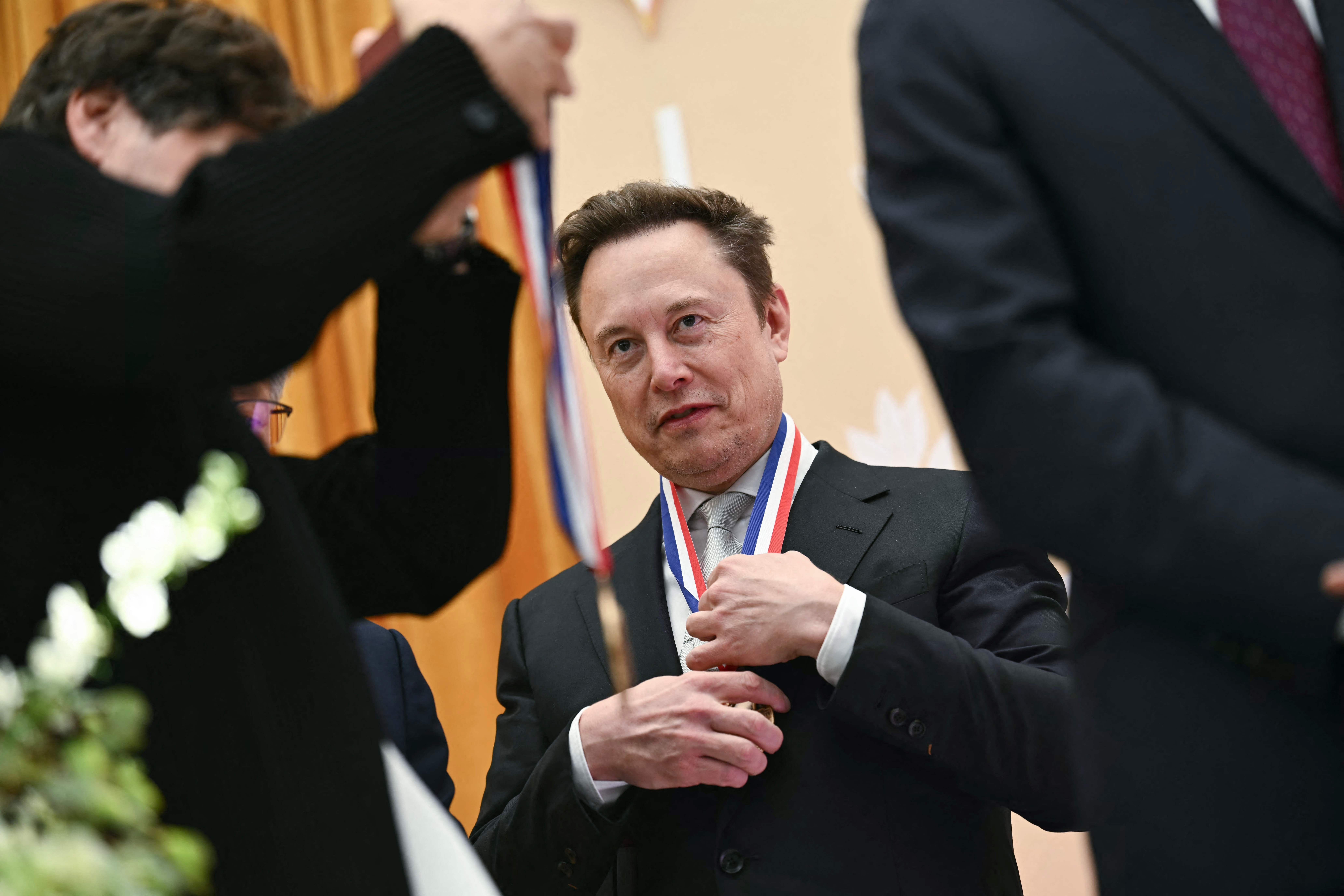 Ein Mann im Anzug erhält eine Medaille mit rot-weiß-blauem Band um den Hals gelegt.