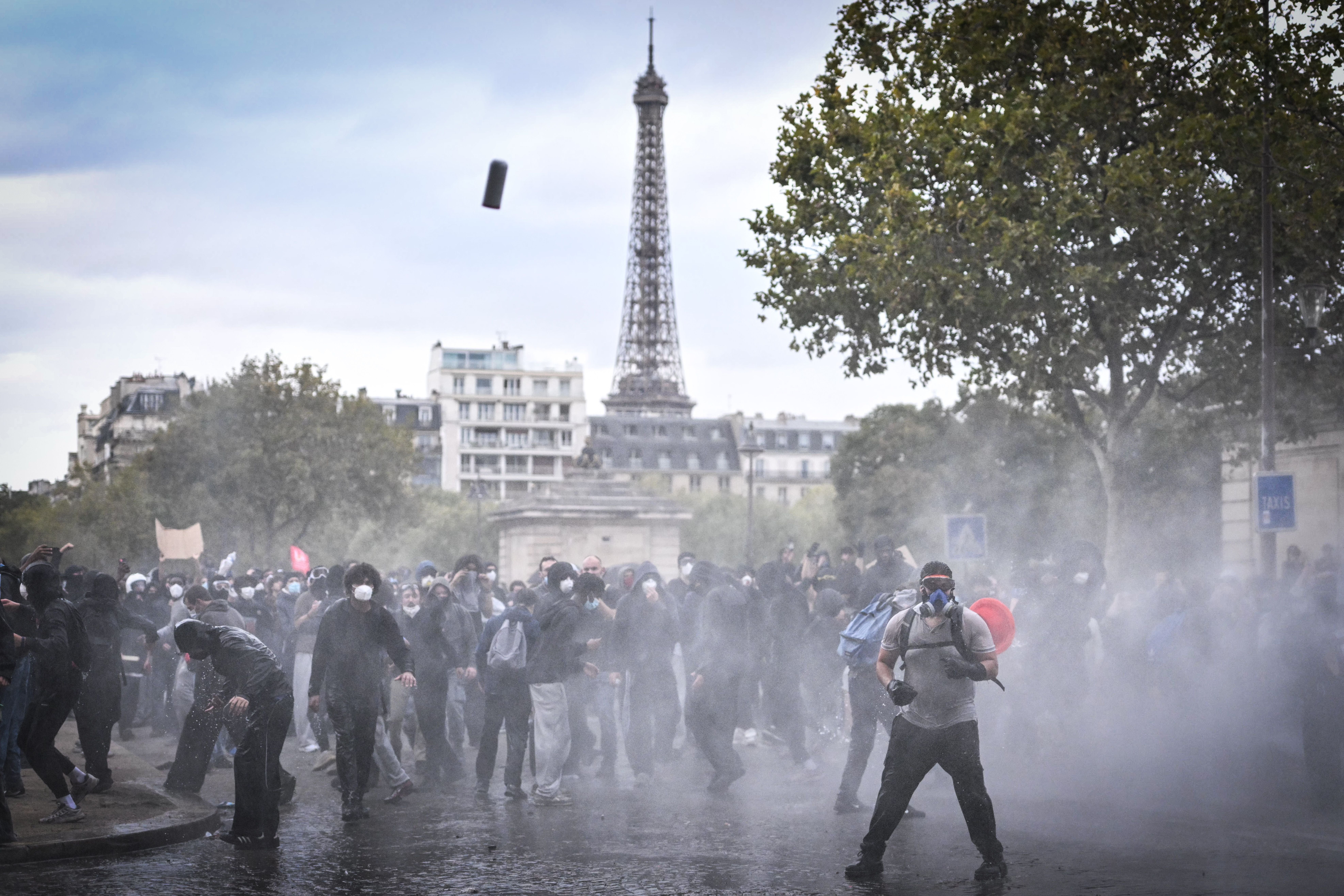 Demonstranten mit Masken und Wasserwerfer-Einsatz vor dem Eiffelturm während eines Protests in Paris.