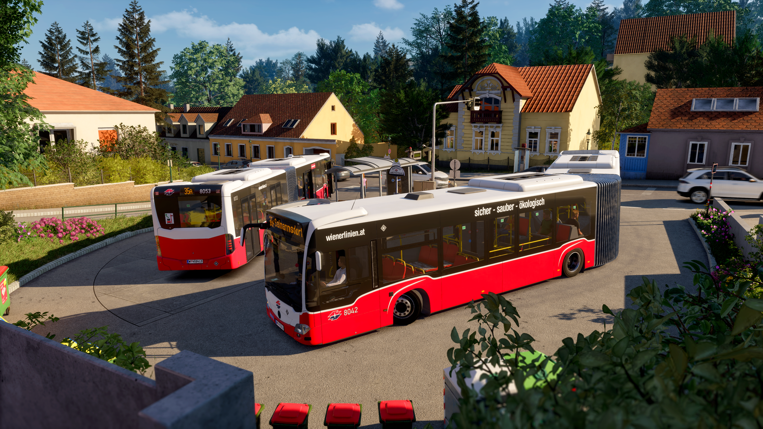 Zwei rot-weiße Gelenkbusse fahren durch einen Kreisverkehr in einem Wohngebiet mit Häusern.