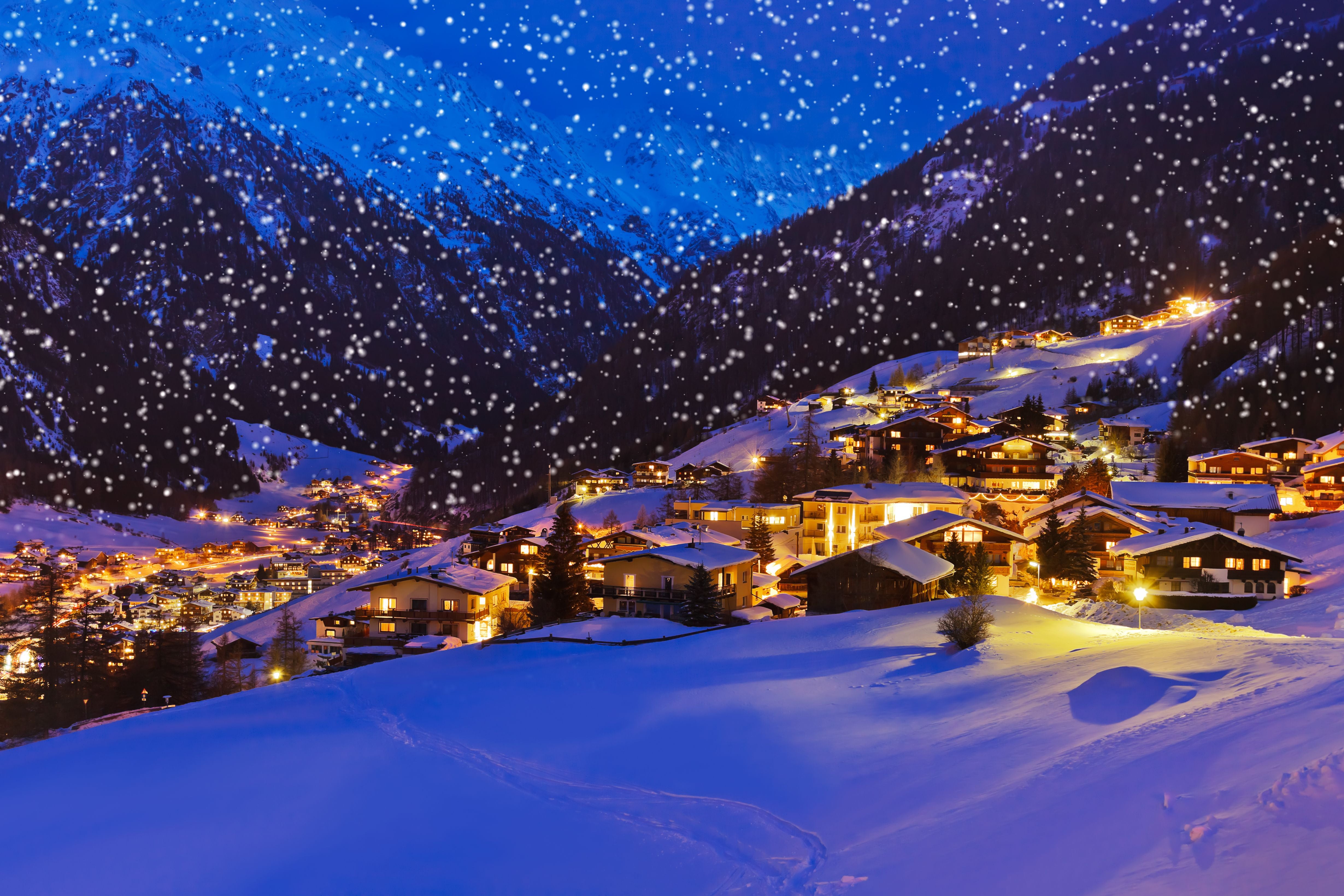 Verschneites Skigebiet Sölden mit beleuchteten Häusern in den Alpen bei Nacht.