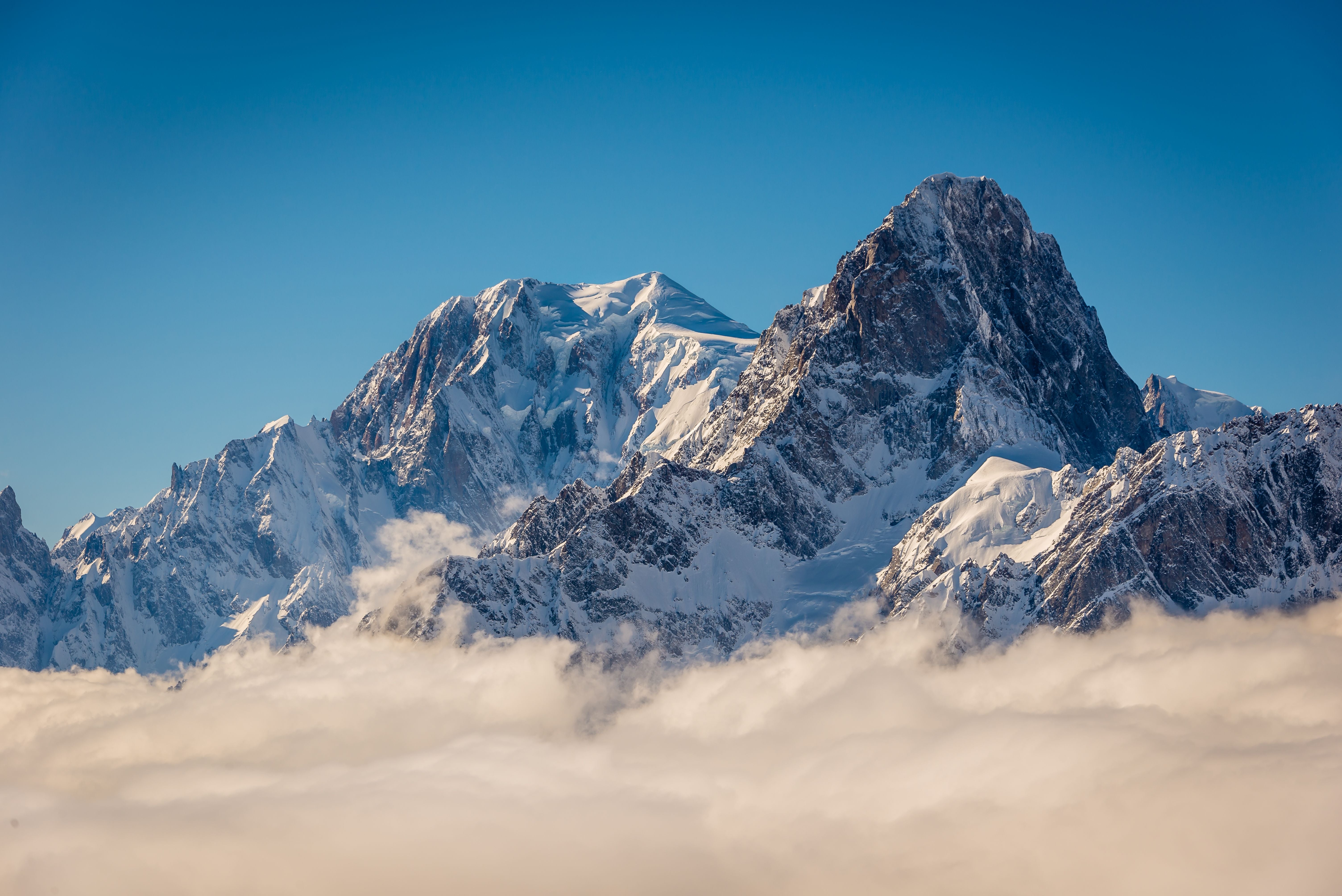 Verschneite Gipfel von Mont Blanc und Grandes Jorasses ragen über winterliche Wolken empor.