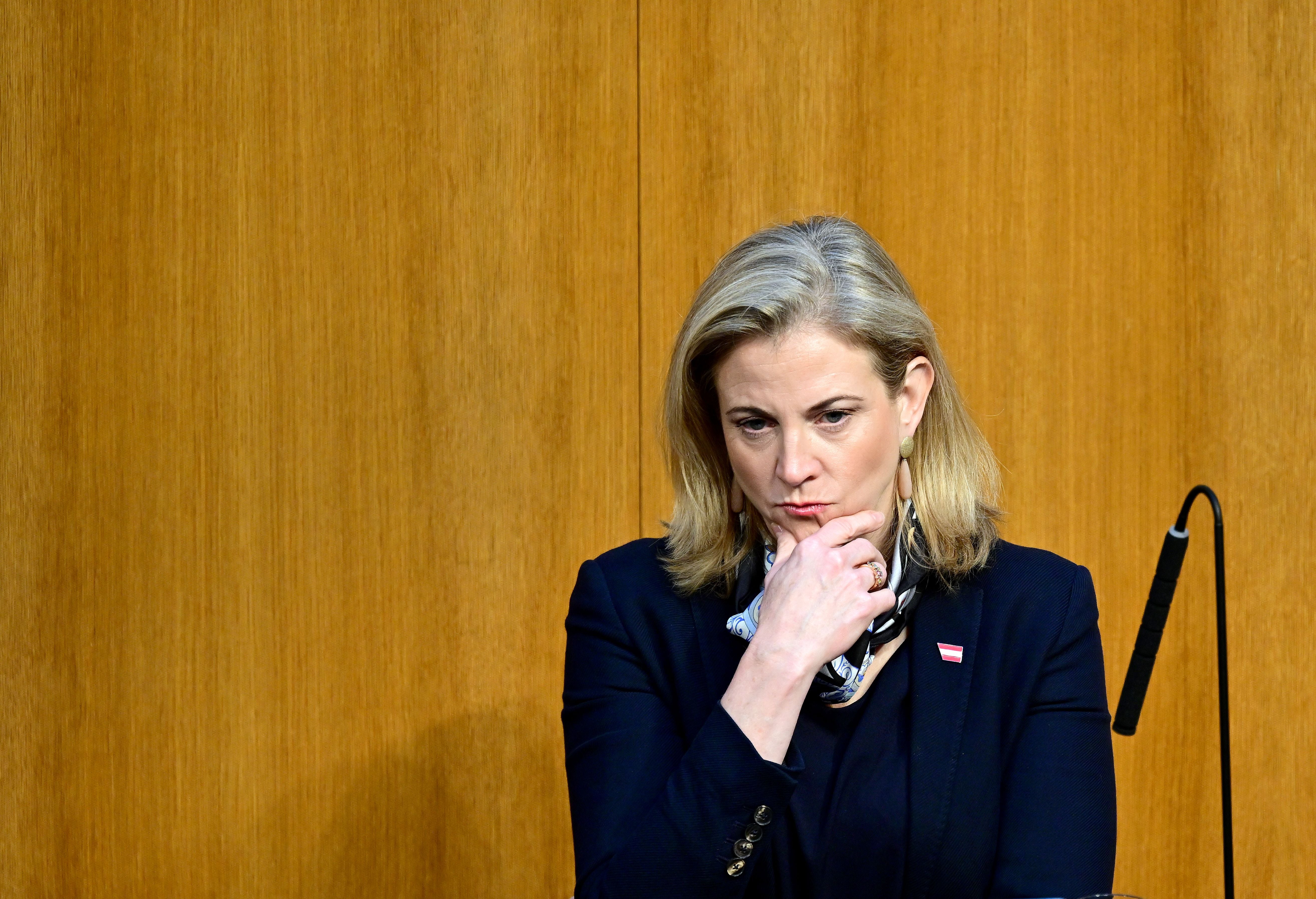 Beate Meinl-Reisinger sitzt nachdenklich im Parlament vor einer Holzvertäfelung.