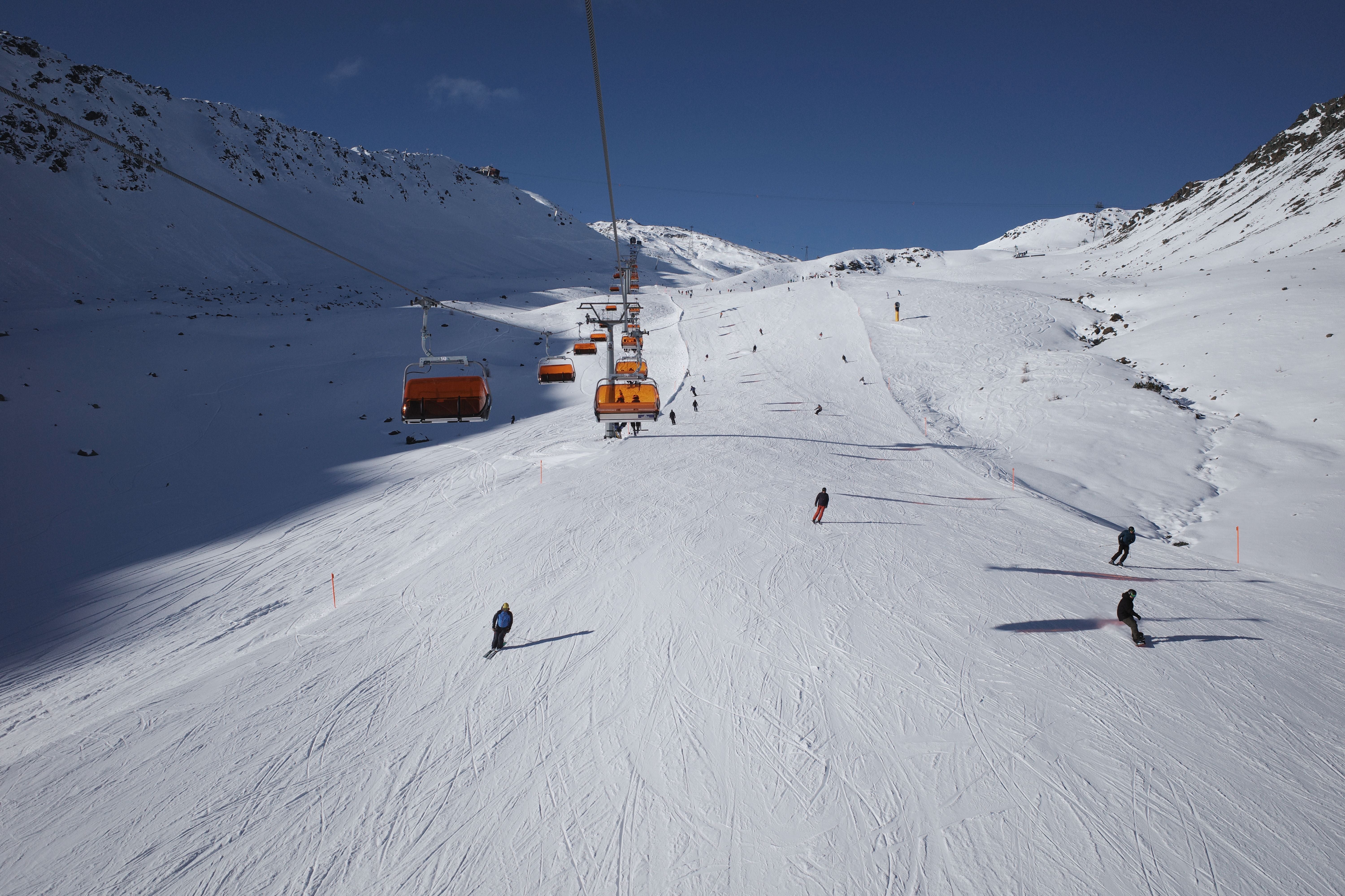 Skifahrer auf verschneiter Piste mit Sessellift in den Bergen von Davos bei blauem Himmel.