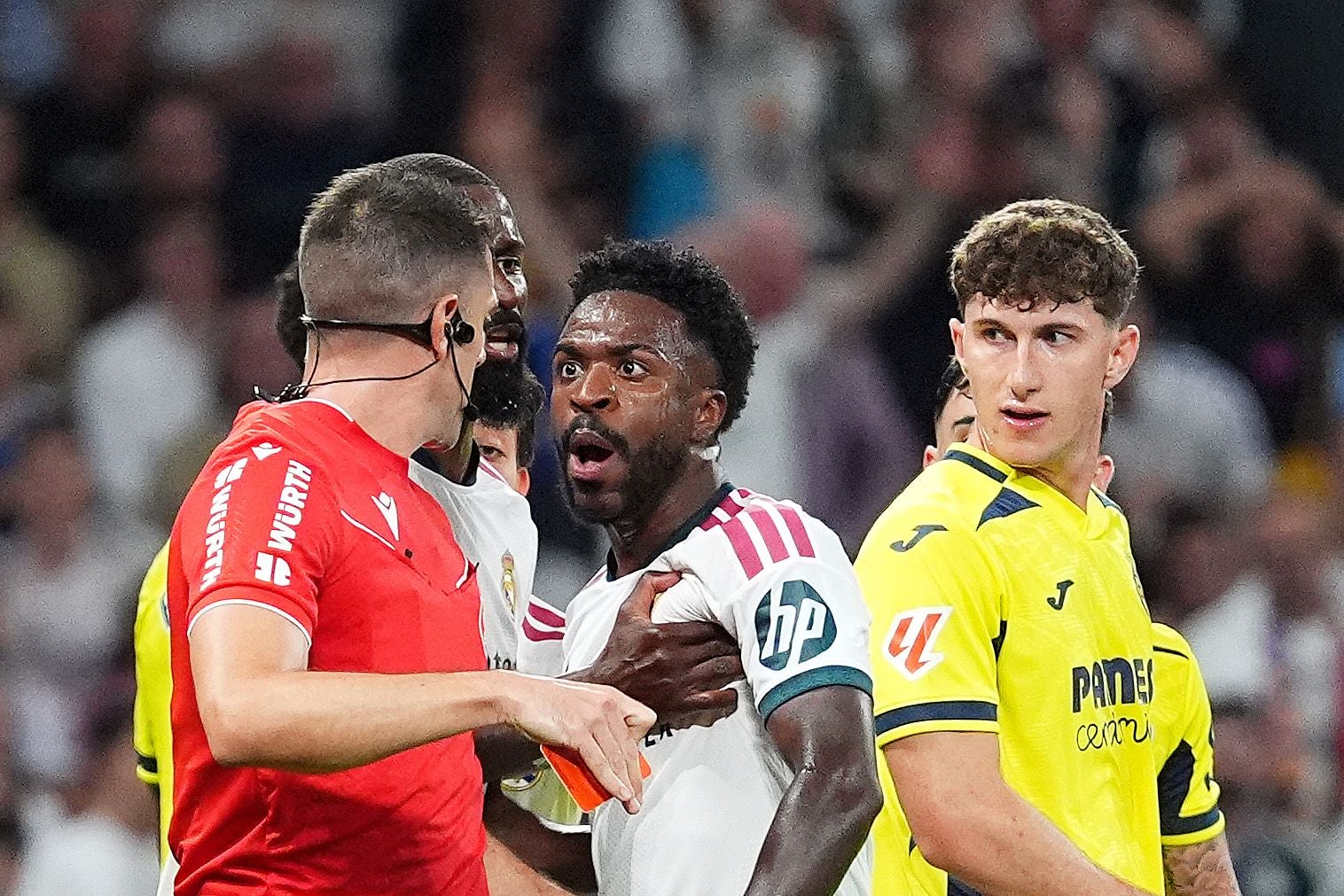 Schiedsrichter zeigt einem Real-Madrid-Spieler die Rote Karte, Spieler reagieren überrascht.