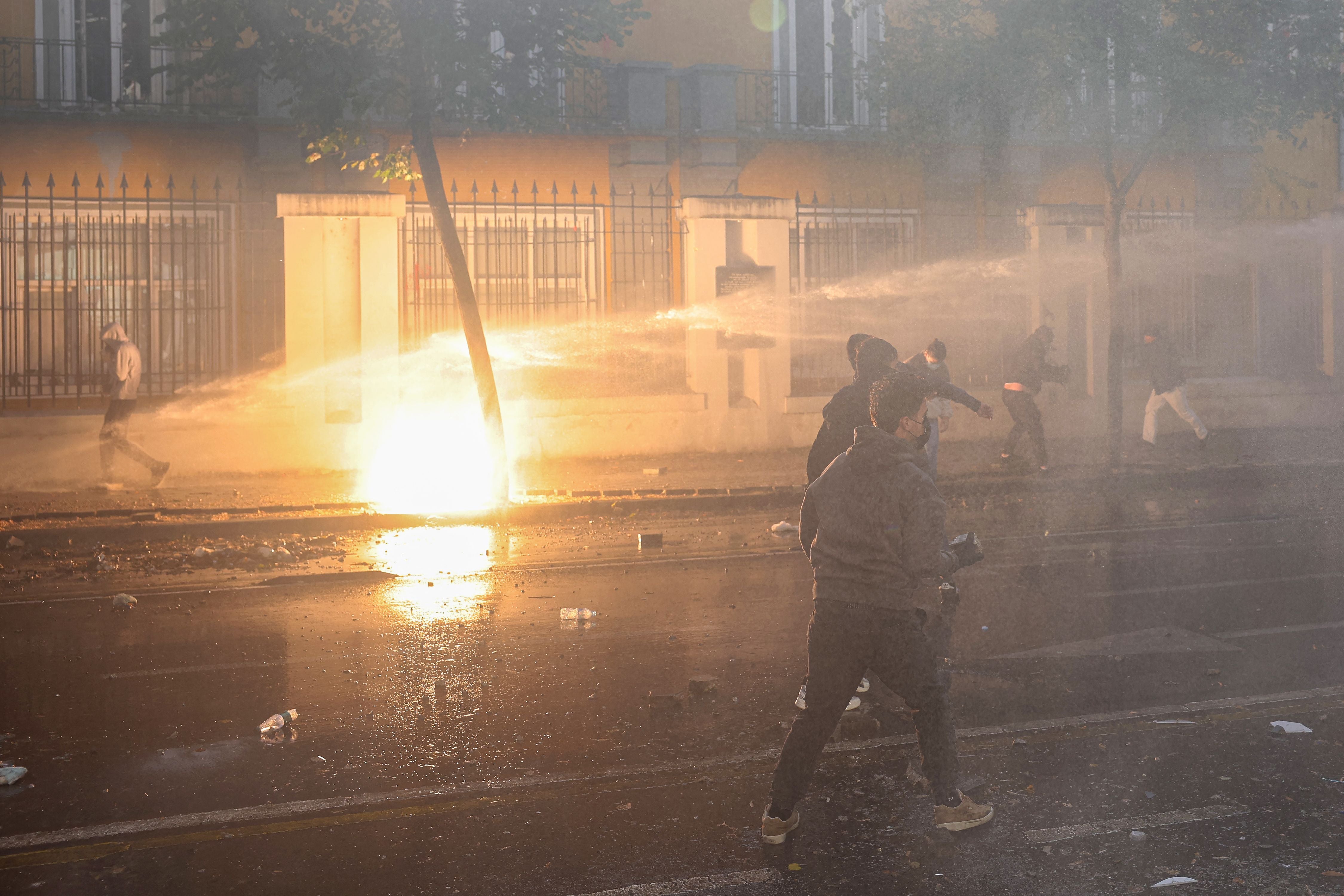 Demonstranten werden bei Protesten in Tirana von einem Wasserwerfer besprüht.