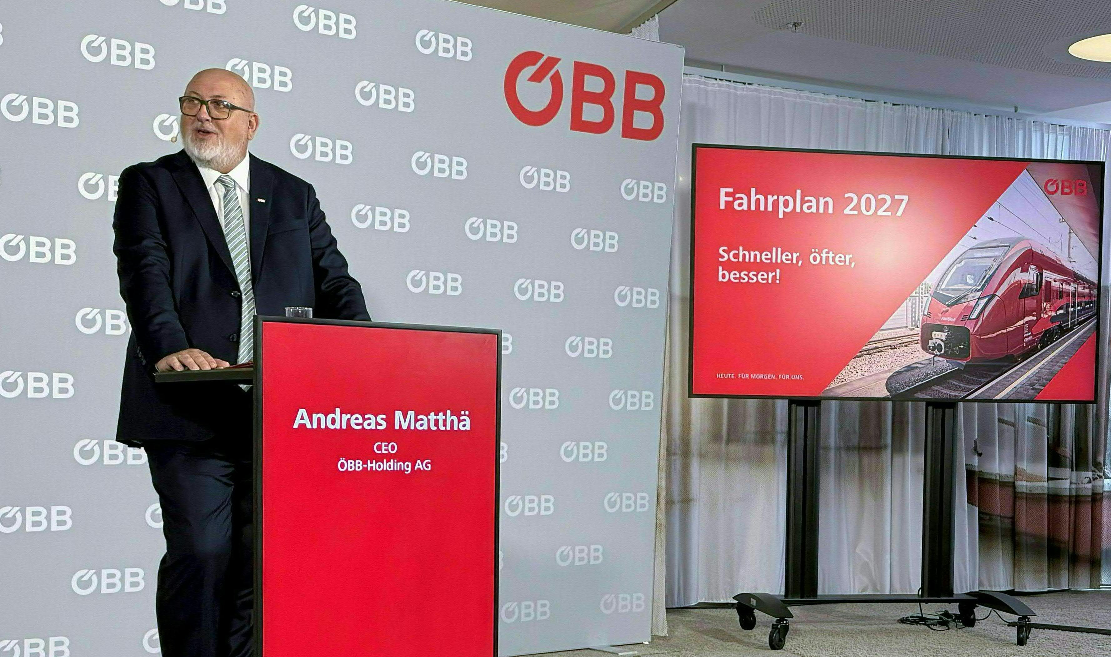 ÖBB-Chef Andreas Matthä präsentiert den Fahrplan 2027 vor einem Bildschirm mit Zugbild.