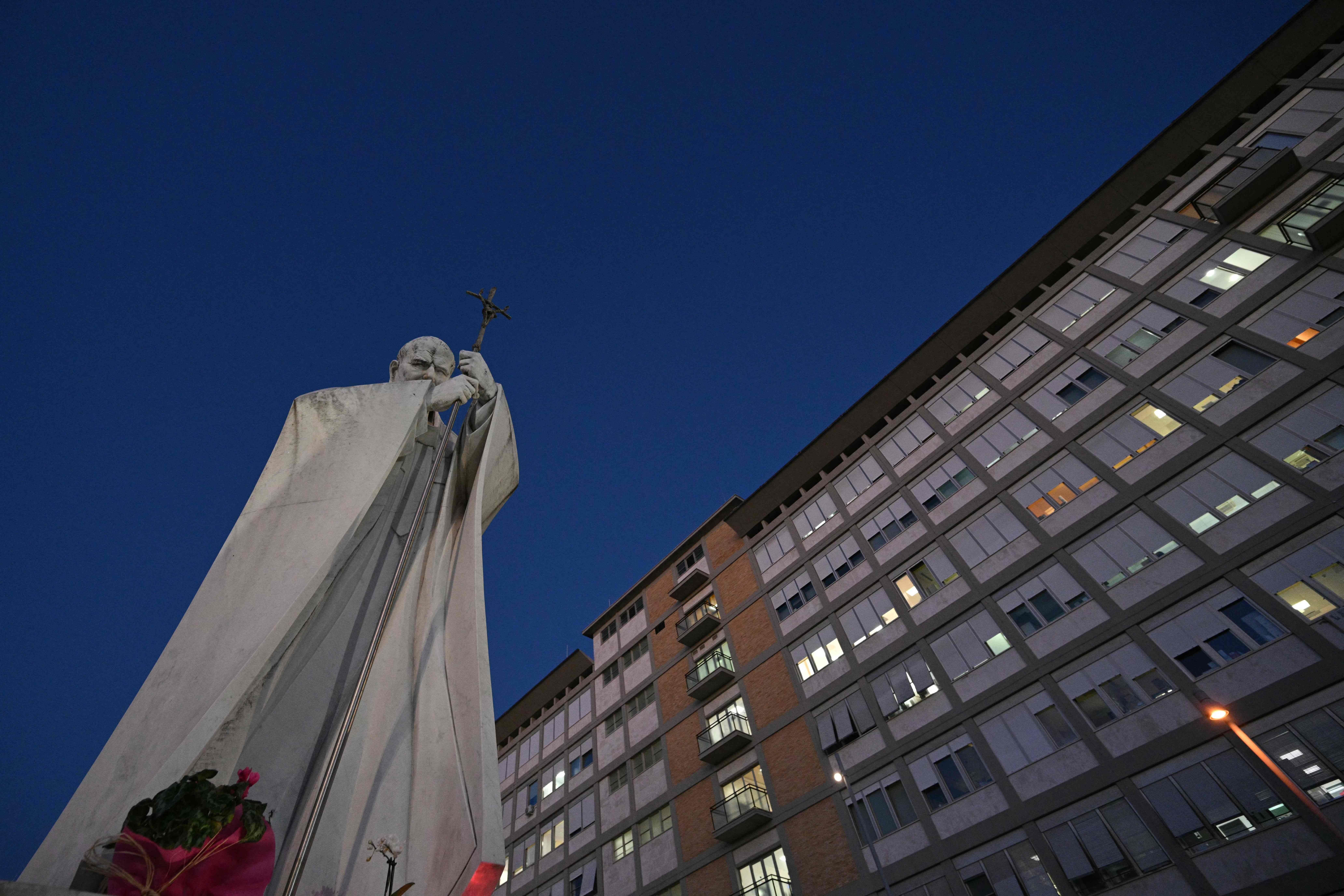 Statue von Johannes Paul II. vor dem Gemelli-Krankenhaus in Rom bei Abenddämmerung.