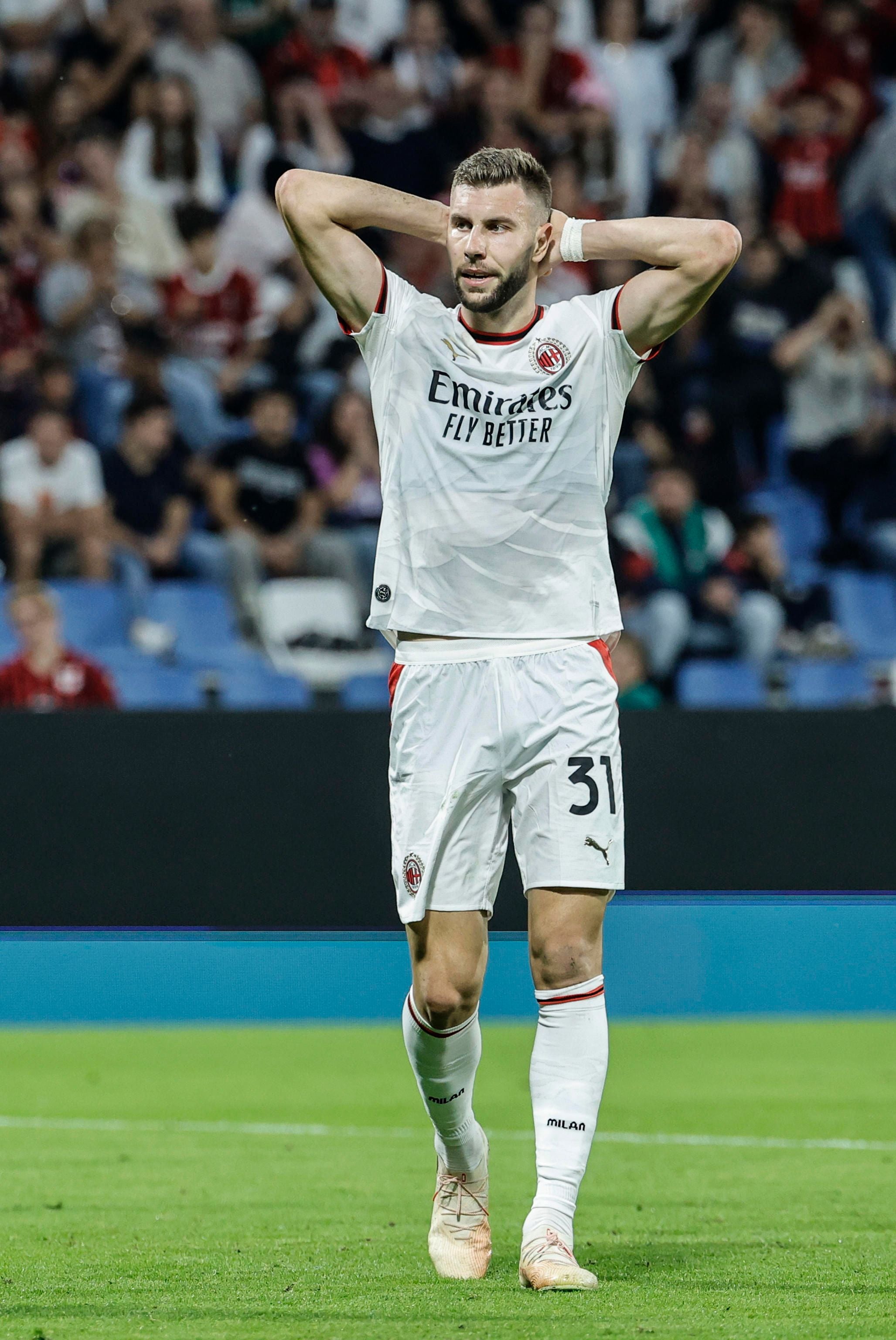 Ein Fußballspieler von AC Milan steht mit den Händen im Nacken auf dem Spielfeld.